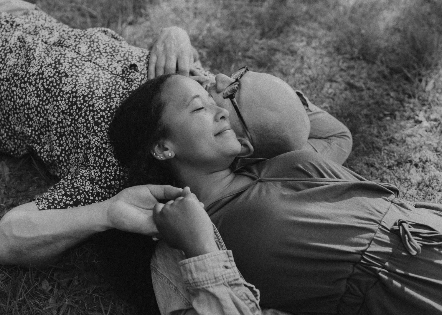 A black and white photo sequence shows a person lying down and rolling in grass, captured in seven continuous frames.