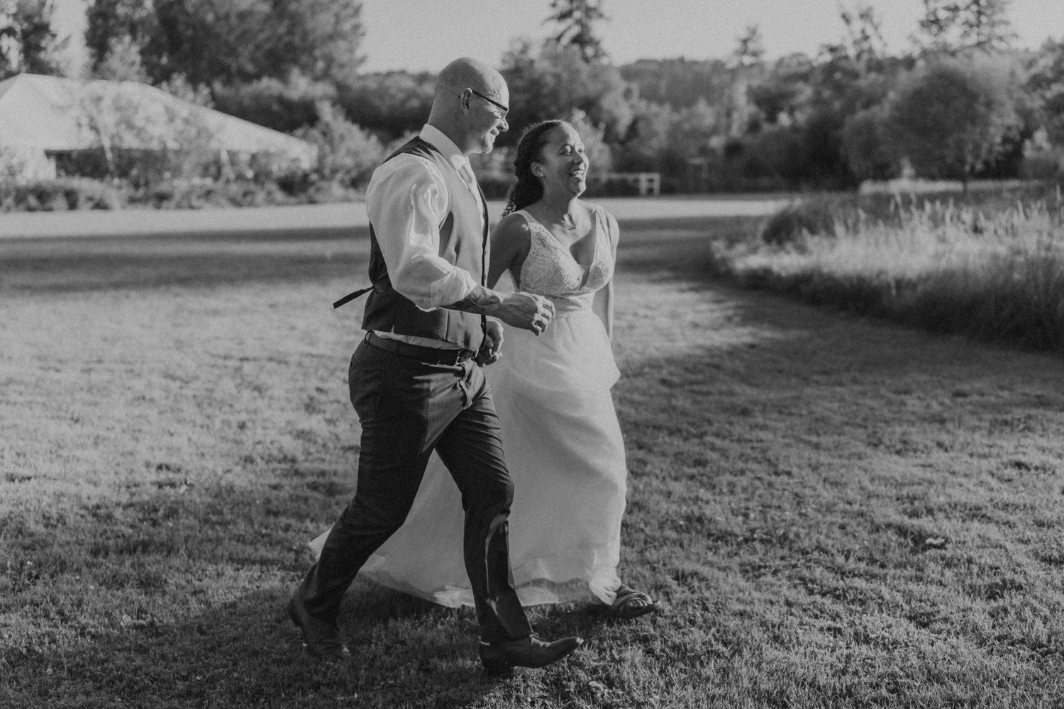 Black and white candid wedding photo of a couple dancing together in a field.