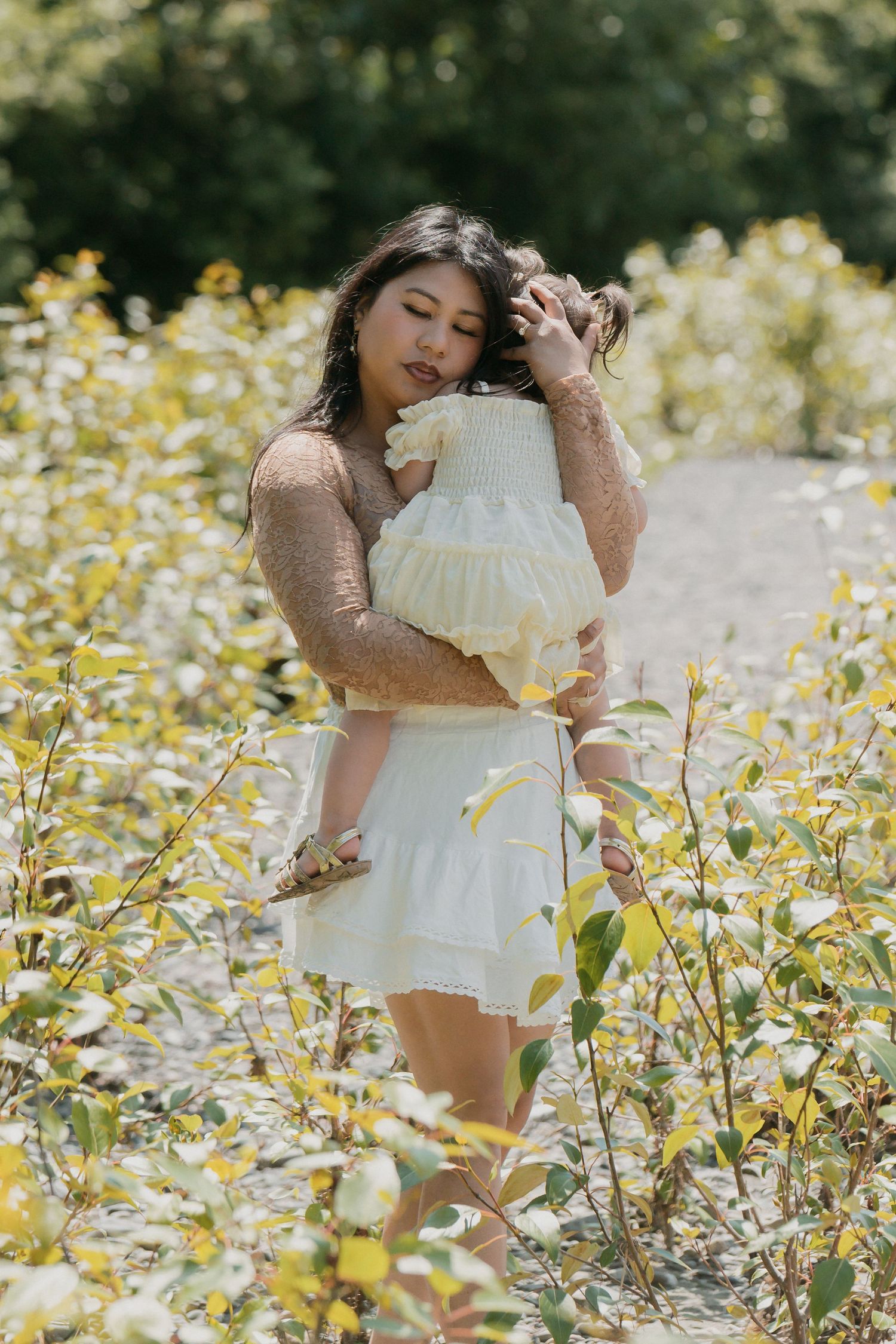 Someone in a white summer dress poses gracefully among blooming yellow wildflowers in a sunlit meadow.