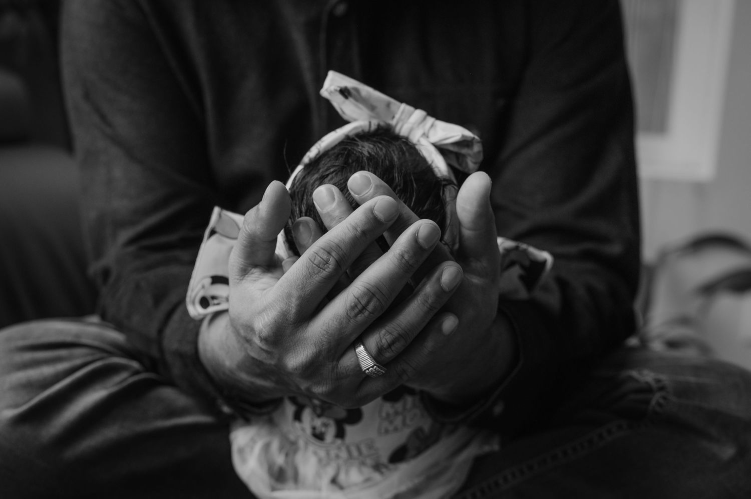 A close-up black and white image of hands gently holding a small bundle.