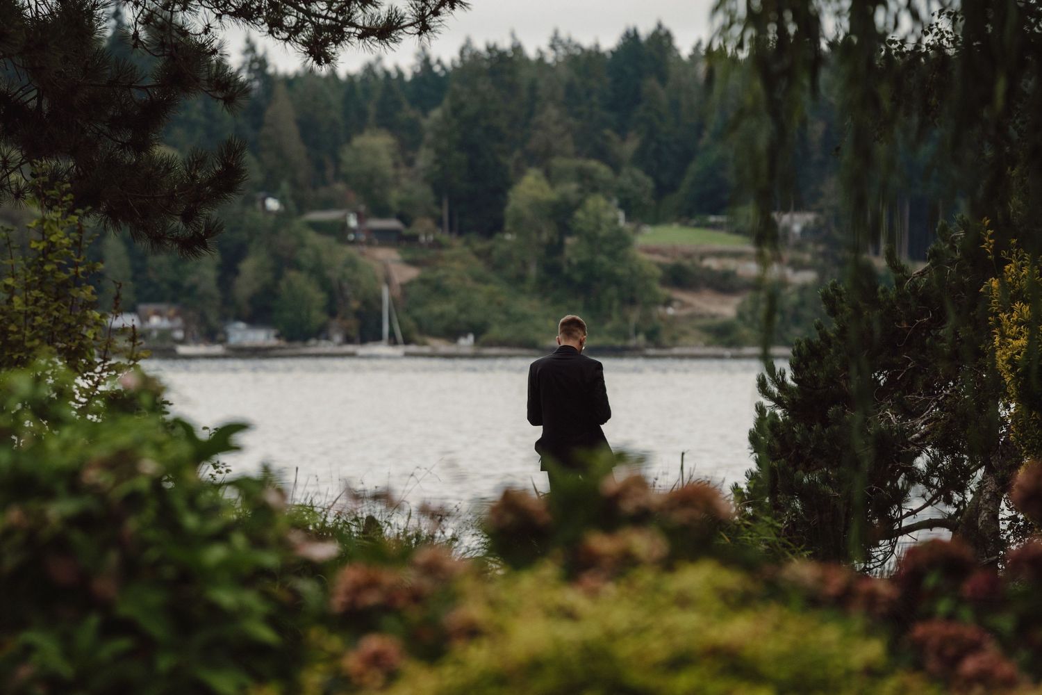 Scenic waterfront homes and docks along a forested lake shore on a cloudy Pacific Northwest day.