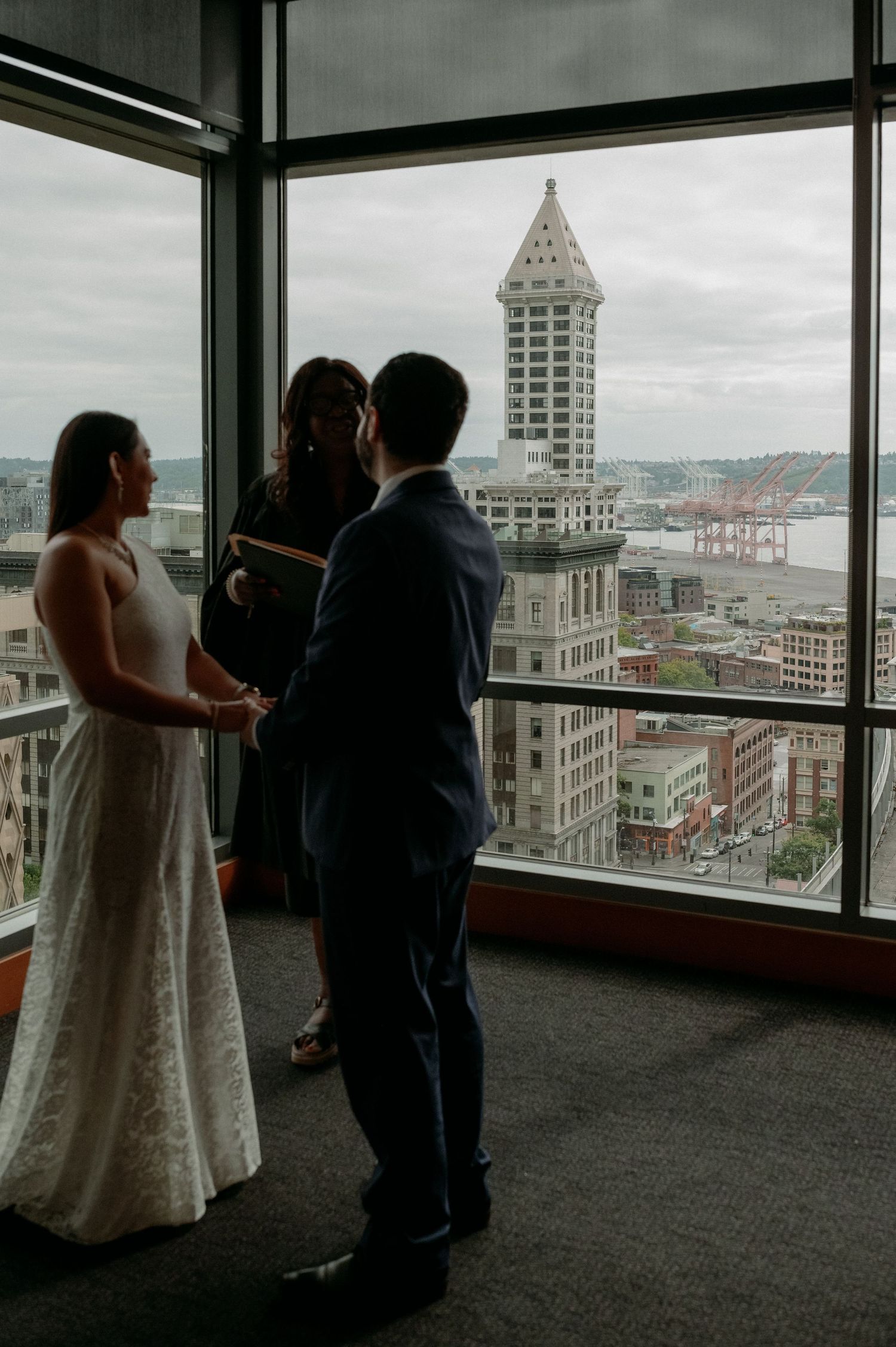 A couple shares a romantic moment while overlooking the city skyline from a high-rise window in cloudy weather.