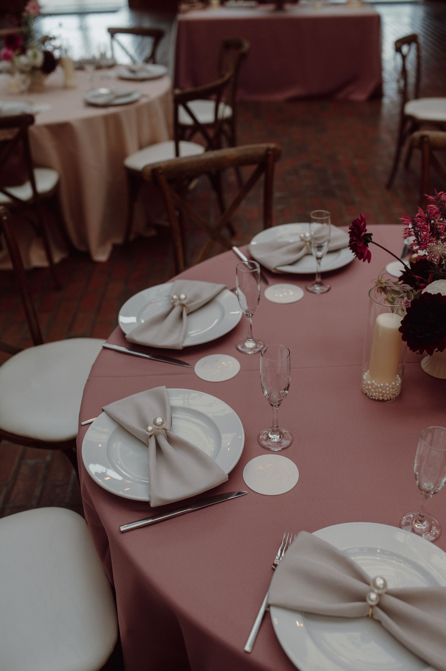 Elegant table setting with mauve tablecloth, white plates, and coordinating napkins for an upscale dining event.