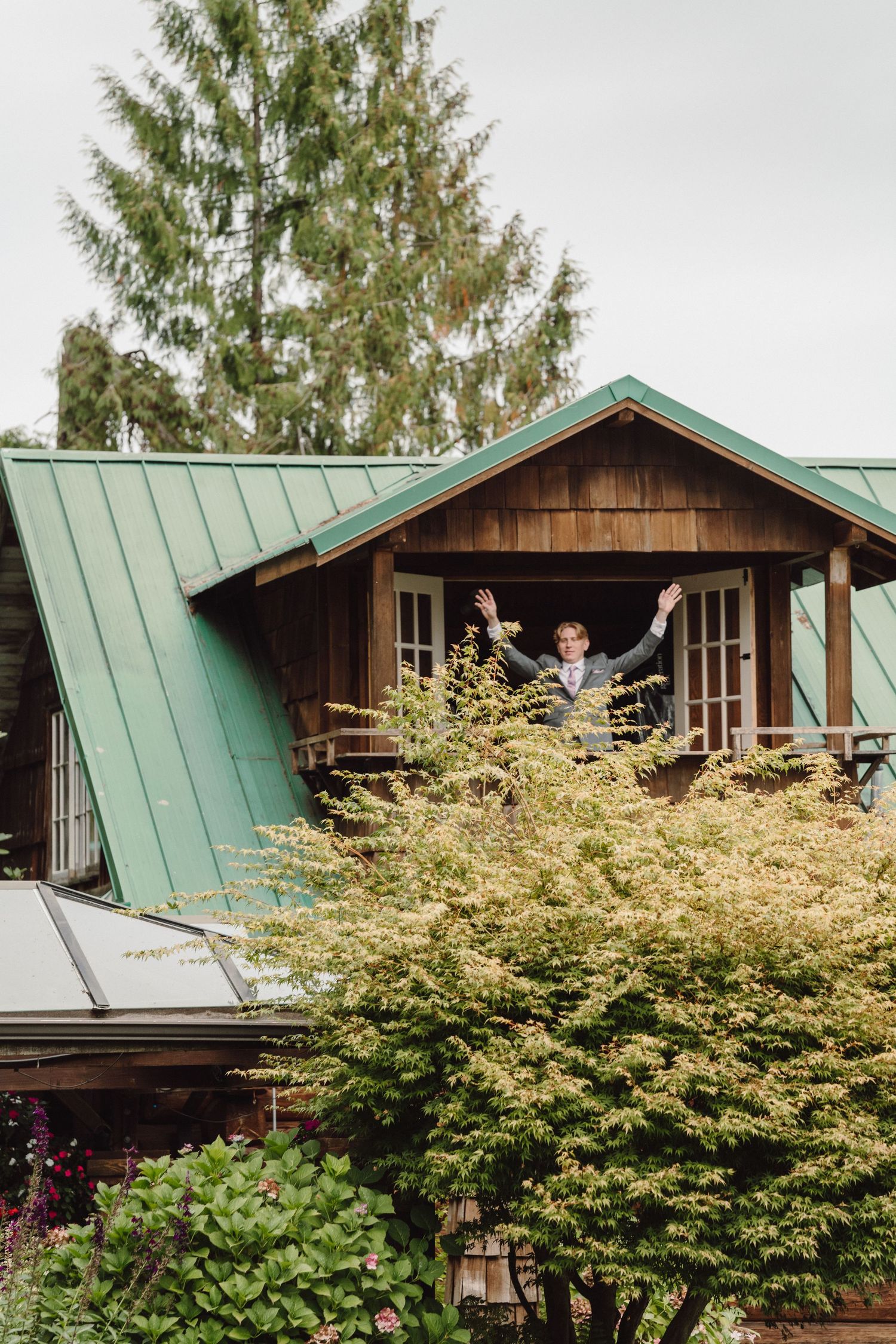 A rustic wooden cabin with green metal roof and surrounding maple trees in natural setting.