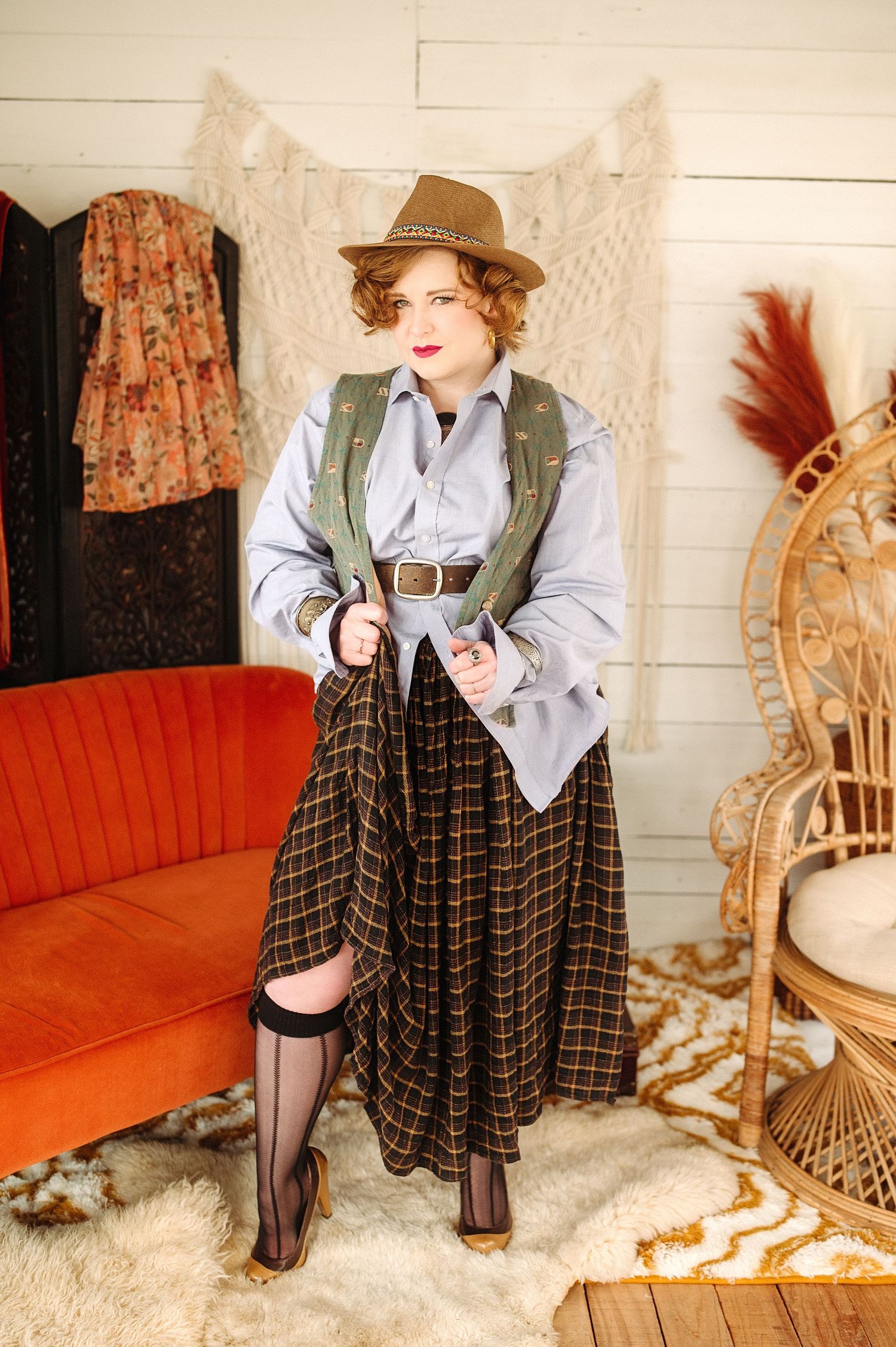 Vintage inspired fashion photo series featuring plaid overalls, brown hat, and white blouse against orange couch backdrop.