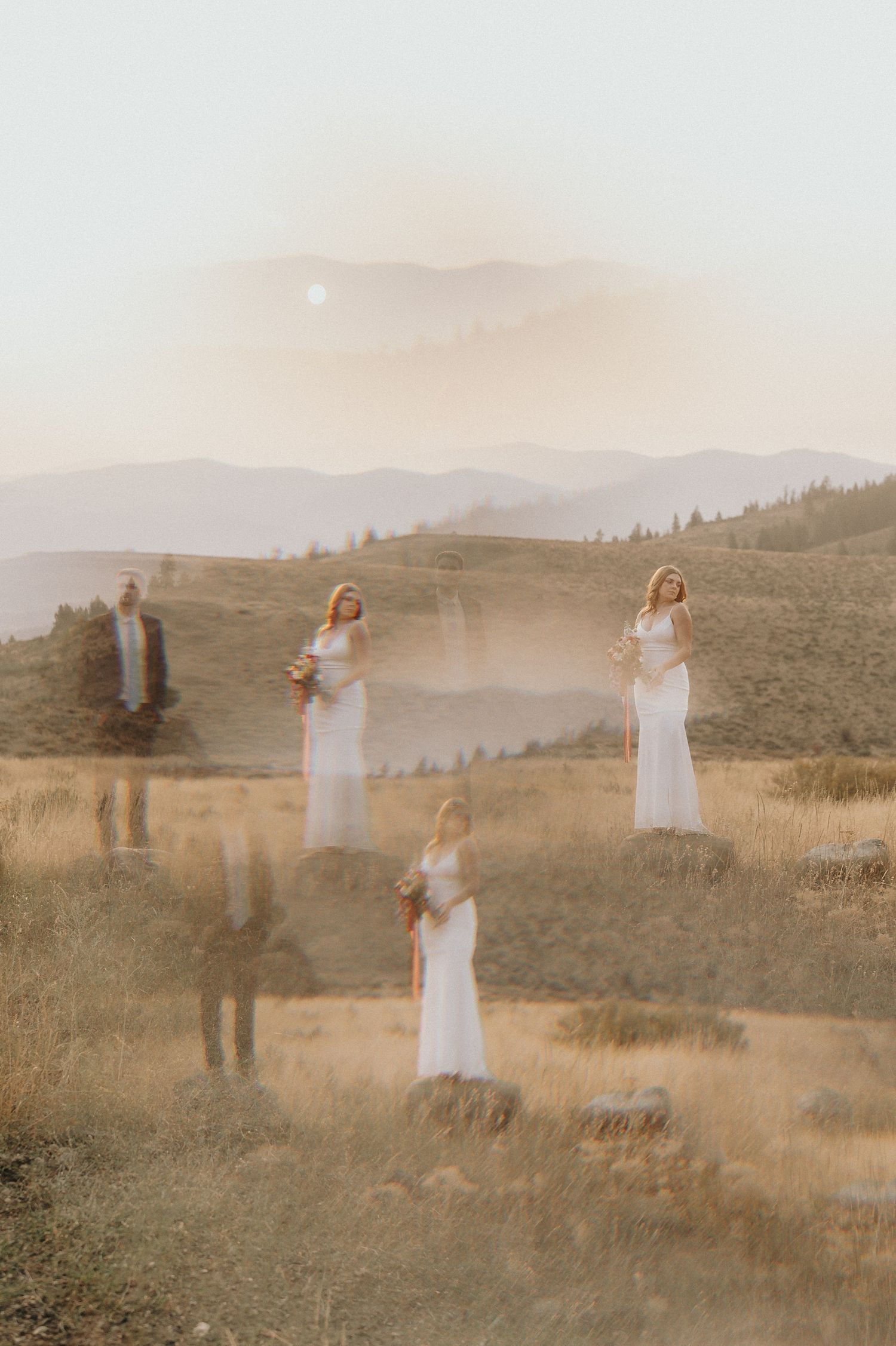 A couple poses together in a dreamy mountain meadow at sunset with soft golden light filtering through the scene.