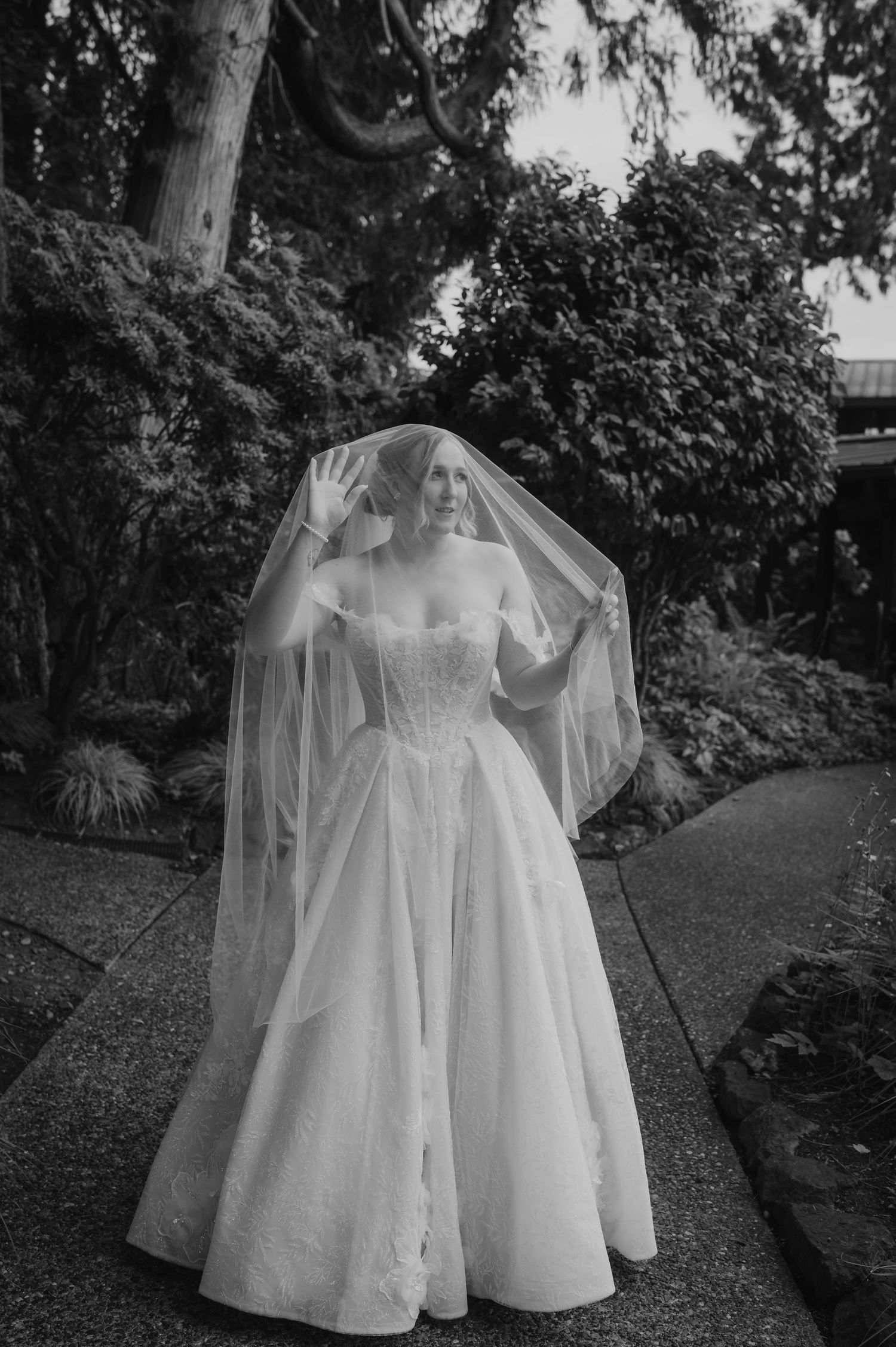 A series of vintage white cotton dresses and baptismal gowns hanging outdoors in a garden setting.