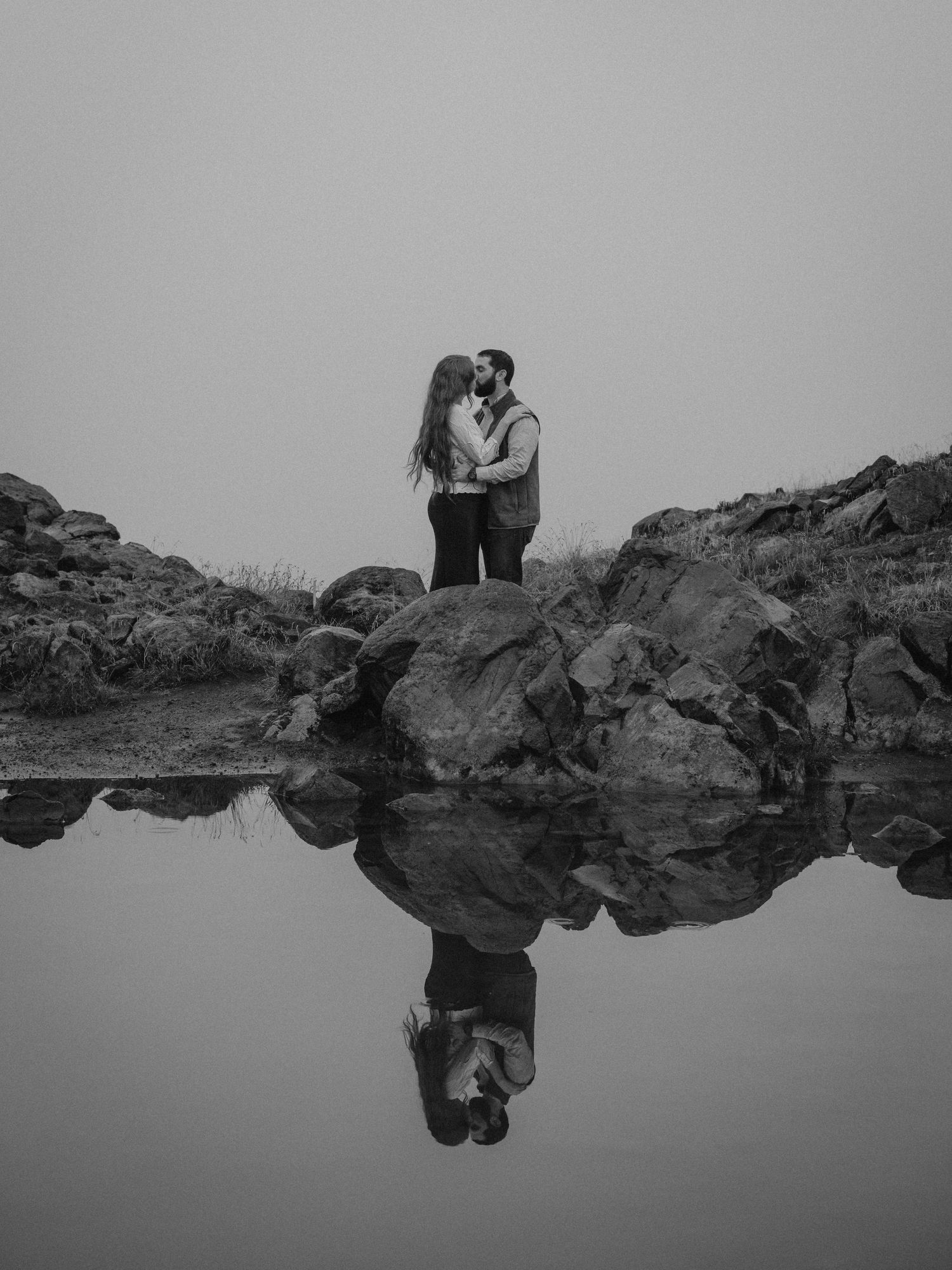 A series of black and white landscape photos showing figures on rocky terrain against a minimalist sky and horizon.