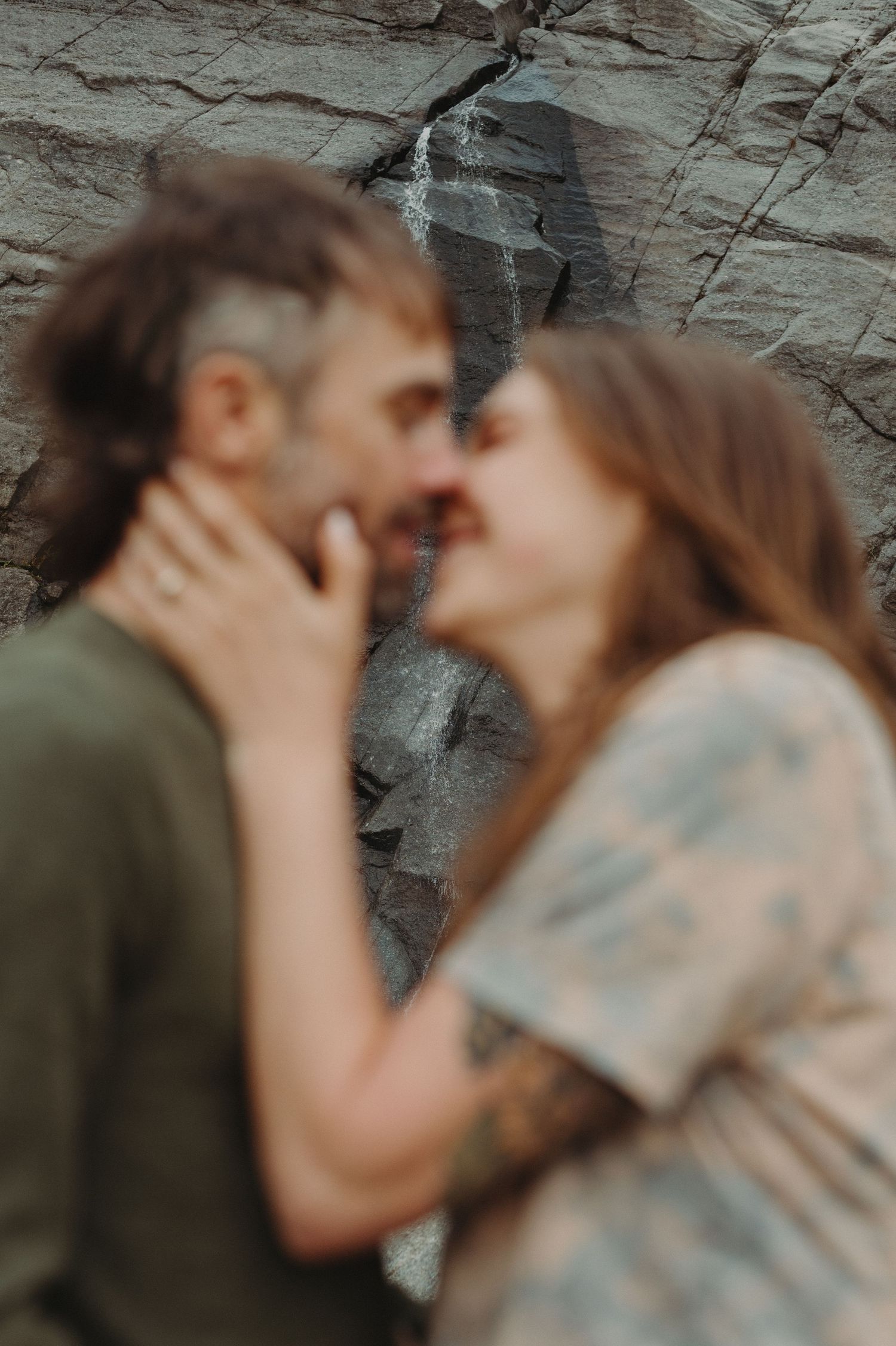 An intimate moment captured against a textured rock wall backdrop.