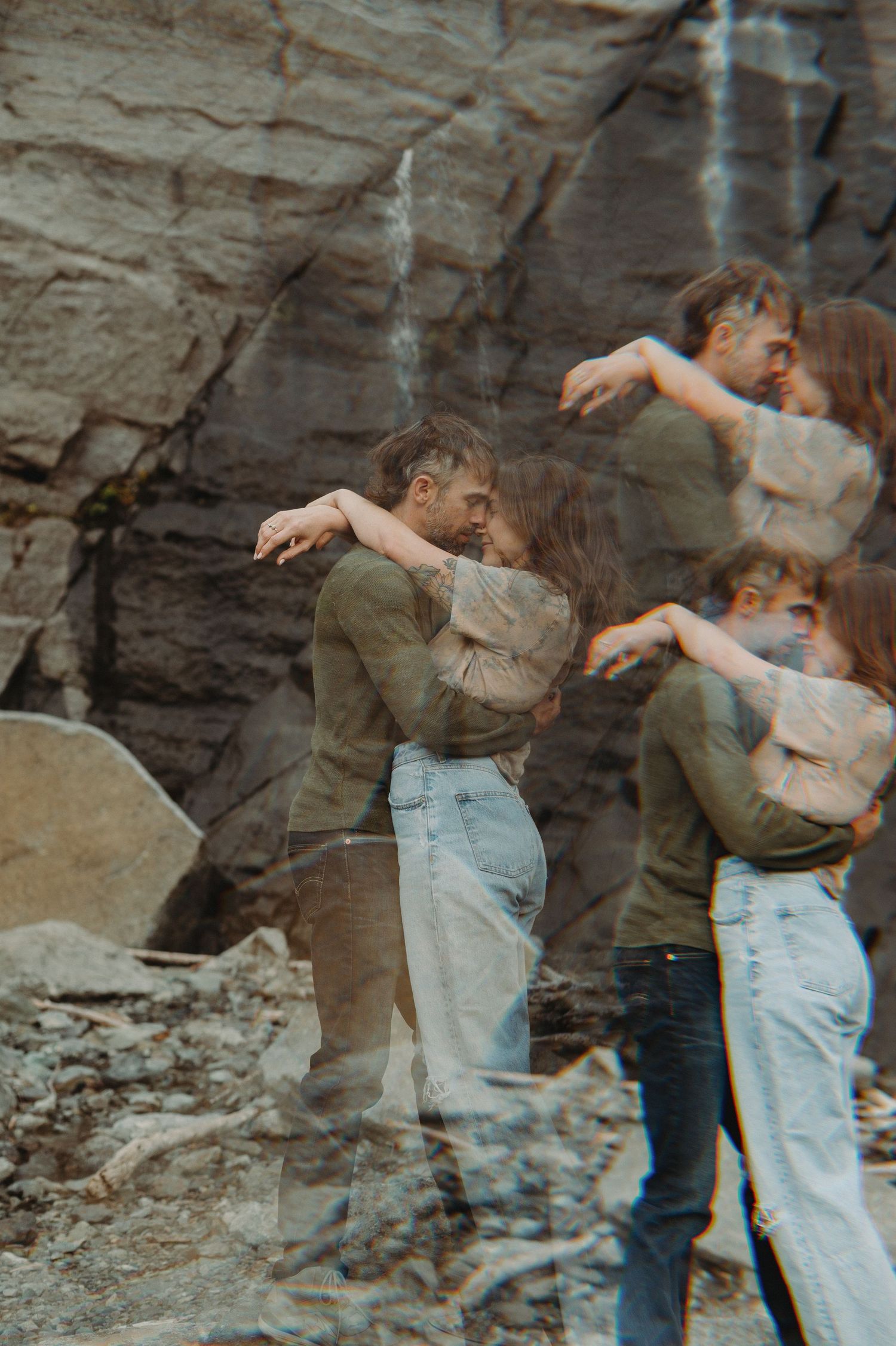 A couple dances together against a rocky cliff backdrop in a romantic outdoor photoshoot.