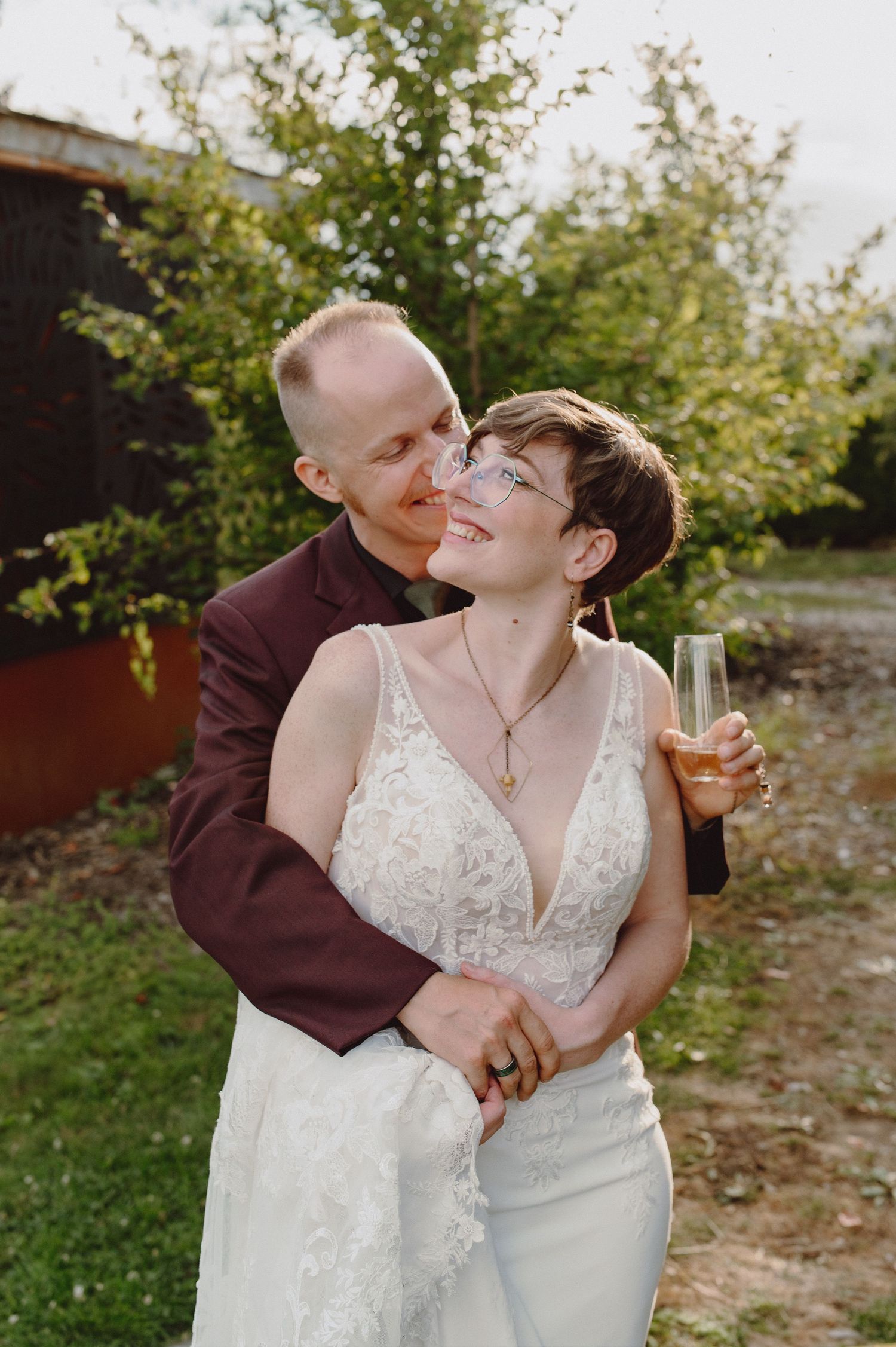Happy couple sharing an intimate moment while holding champagne glasses at their outdoor wedding.