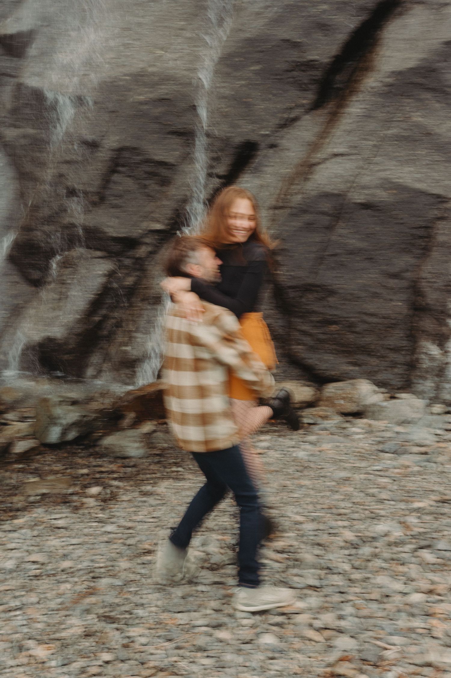 A person in autumn attire spinning joyfully against a rocky cliff background.