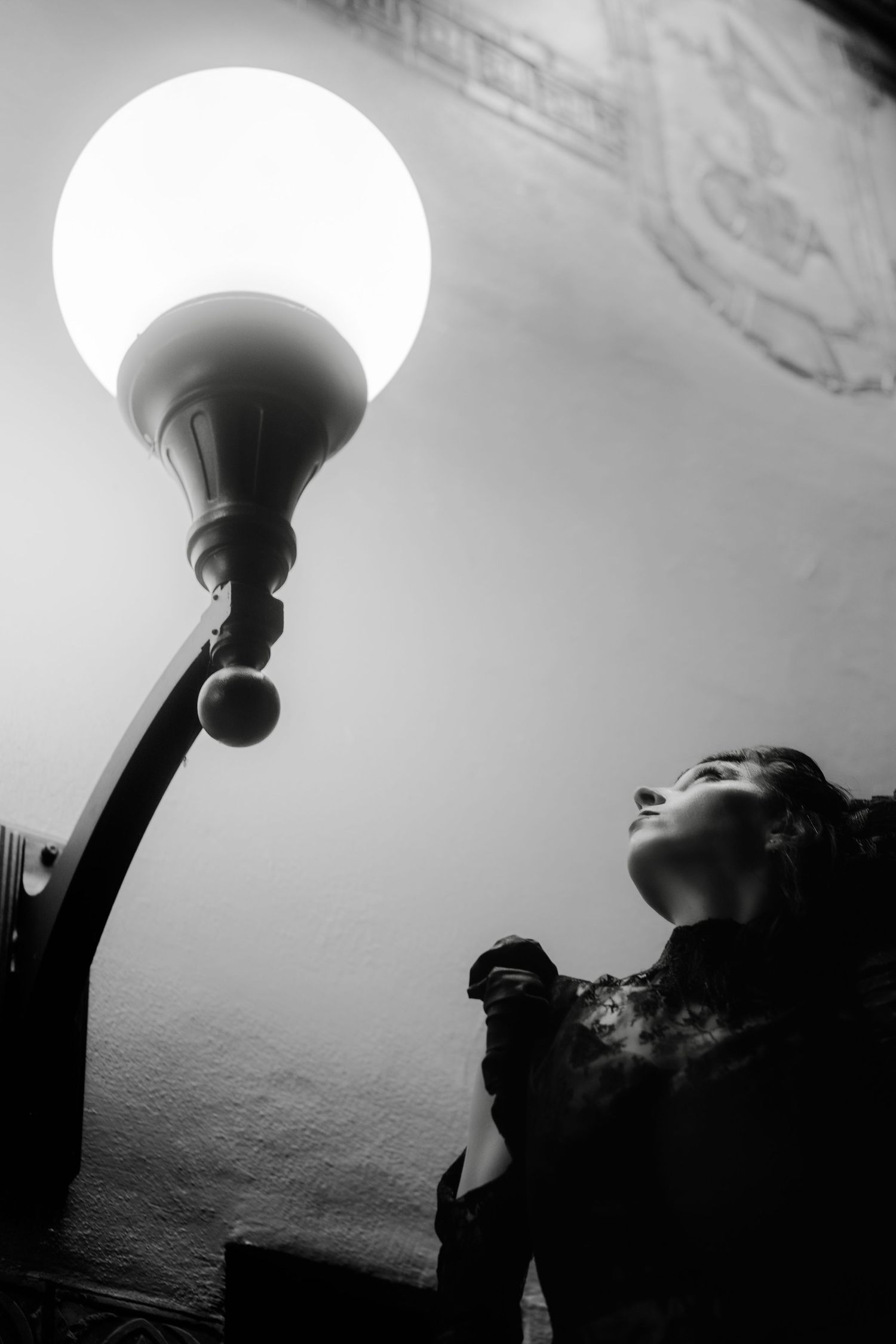 A dramatic black and white series of silhouettes showing someone reaching up towards a glowing ceiling light fixture.