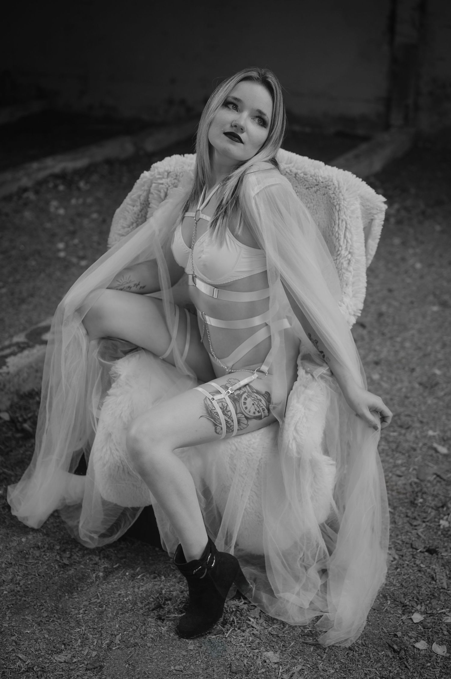 A creative black and white portrait series showing a figure in a flowing white dress and dark boots posed on the ground.