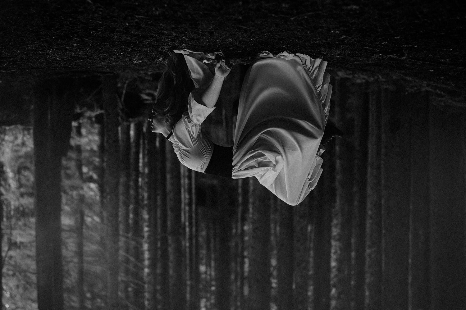 A haunting black and white photograph shows a ghostly white fabric suspended and flowing against a dark background.