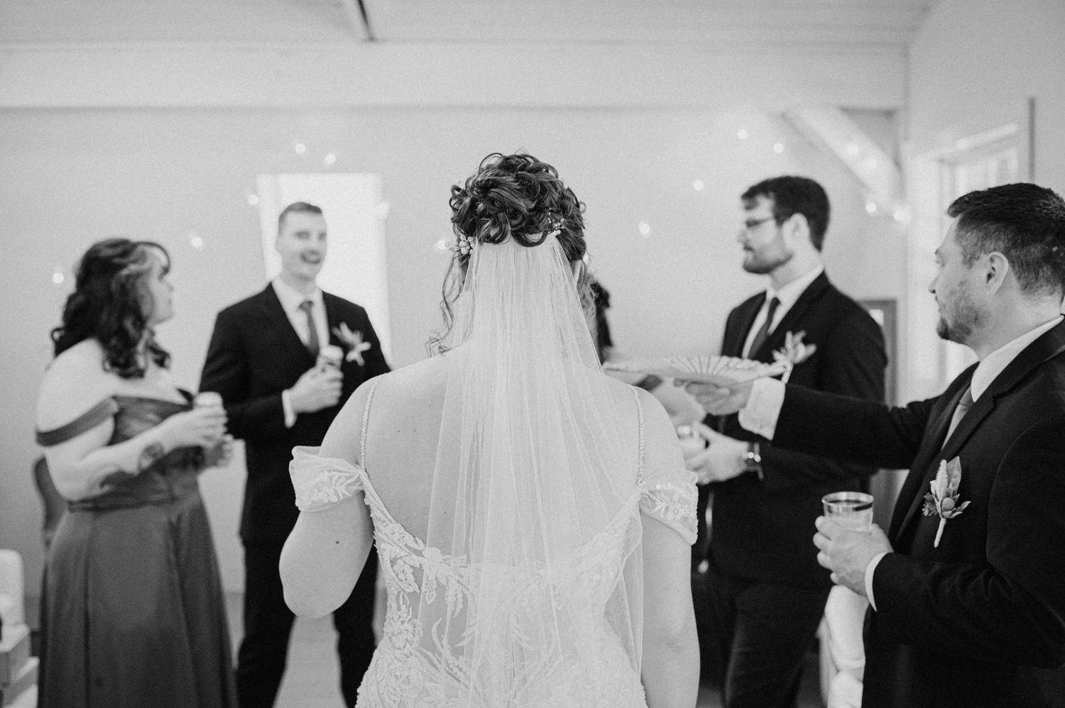 Black and white photo of a bride and wedding party gathered indoors.