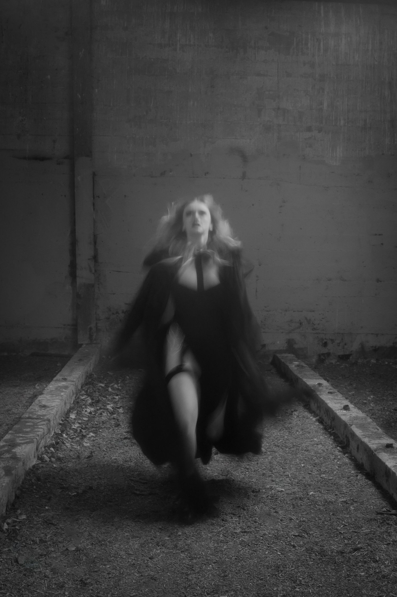A dramatic series of black and white photographs showing a figure in dark clothing moving mysteriously along the ground.