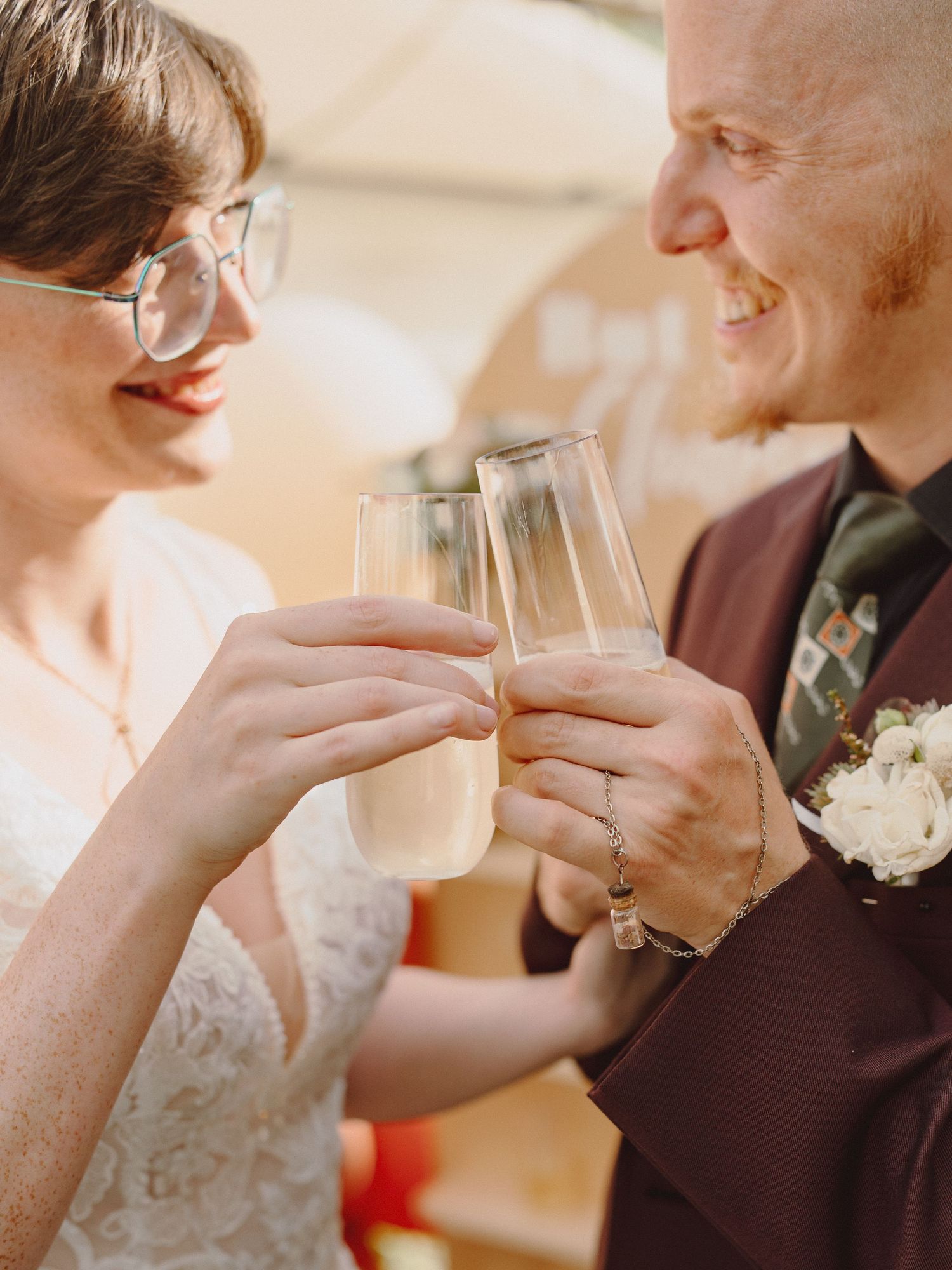 A bride and groom smiling and clinking champagne glasses during their wedding reception celebration.