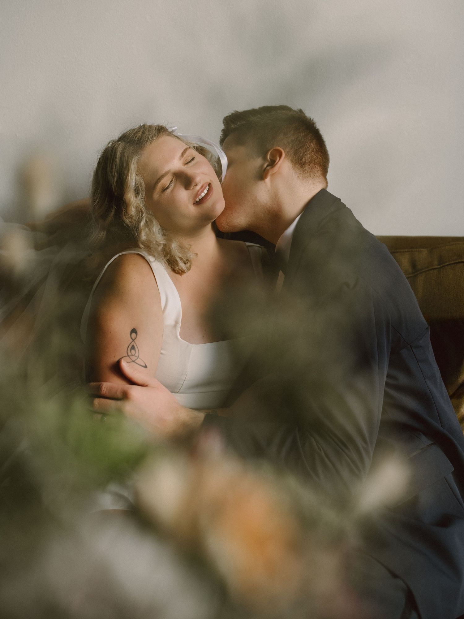An intimate moment captured through foliage with soft, romantic lighting.