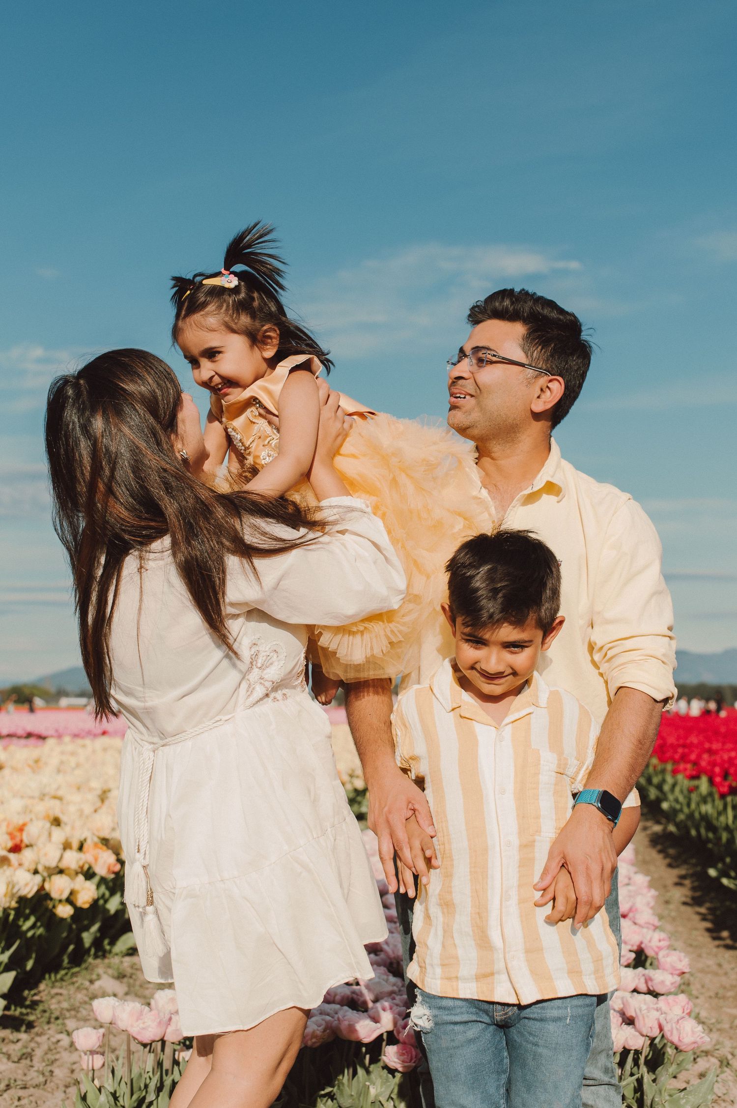A family enjoying a sunny day together in a flower field with colorful tulips blooming.
