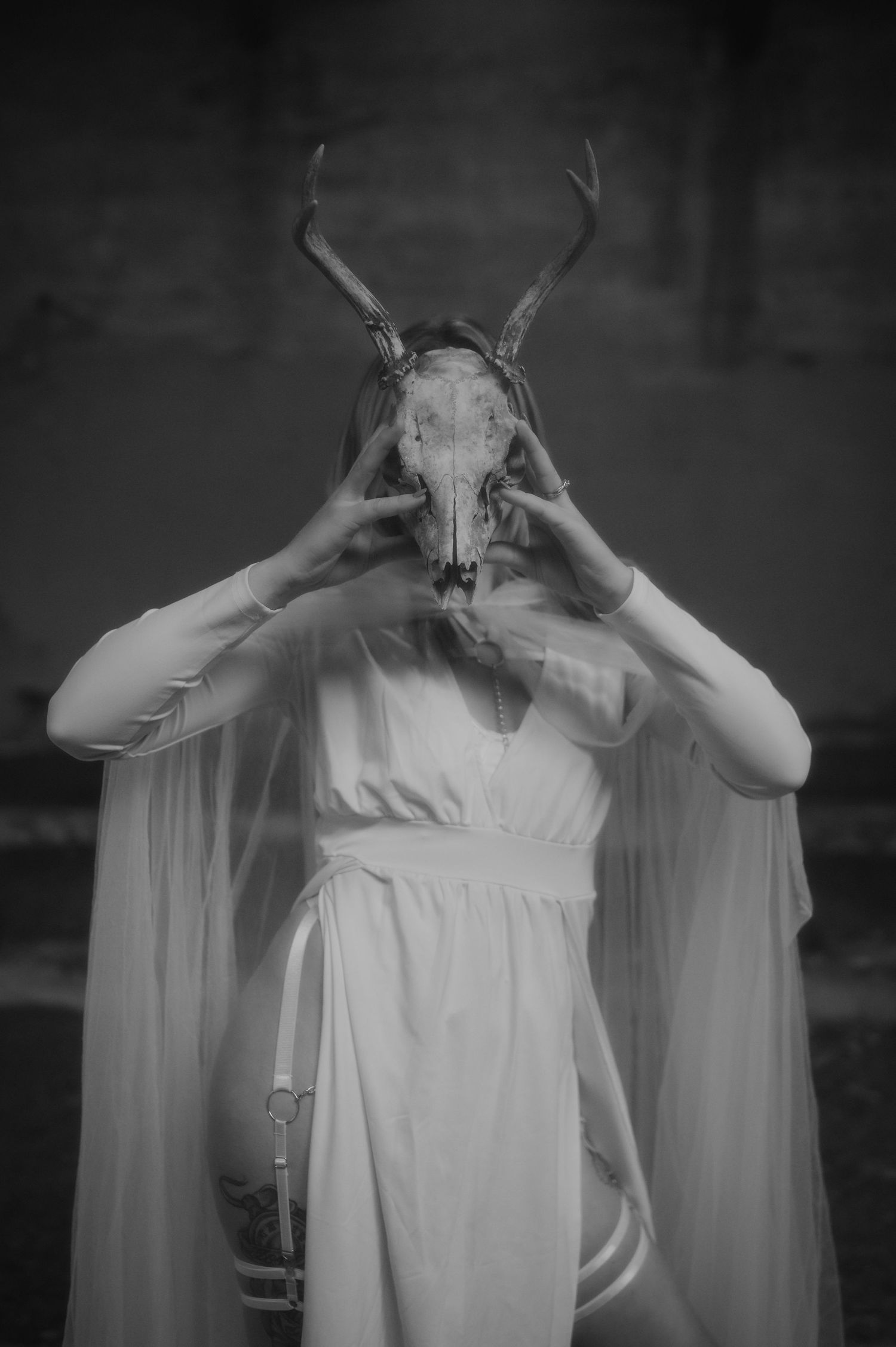 Four black and white images showing a figure in a white flowing dress making dramatic gestures with their hands.