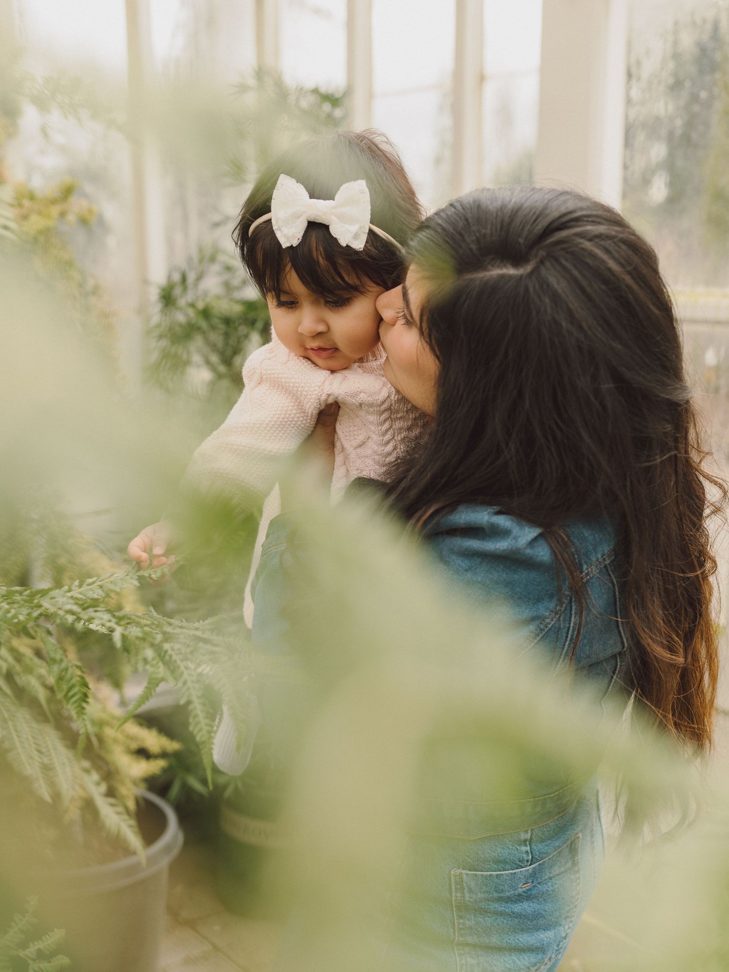 Sweet candid moment between parent and child among indoor plants.