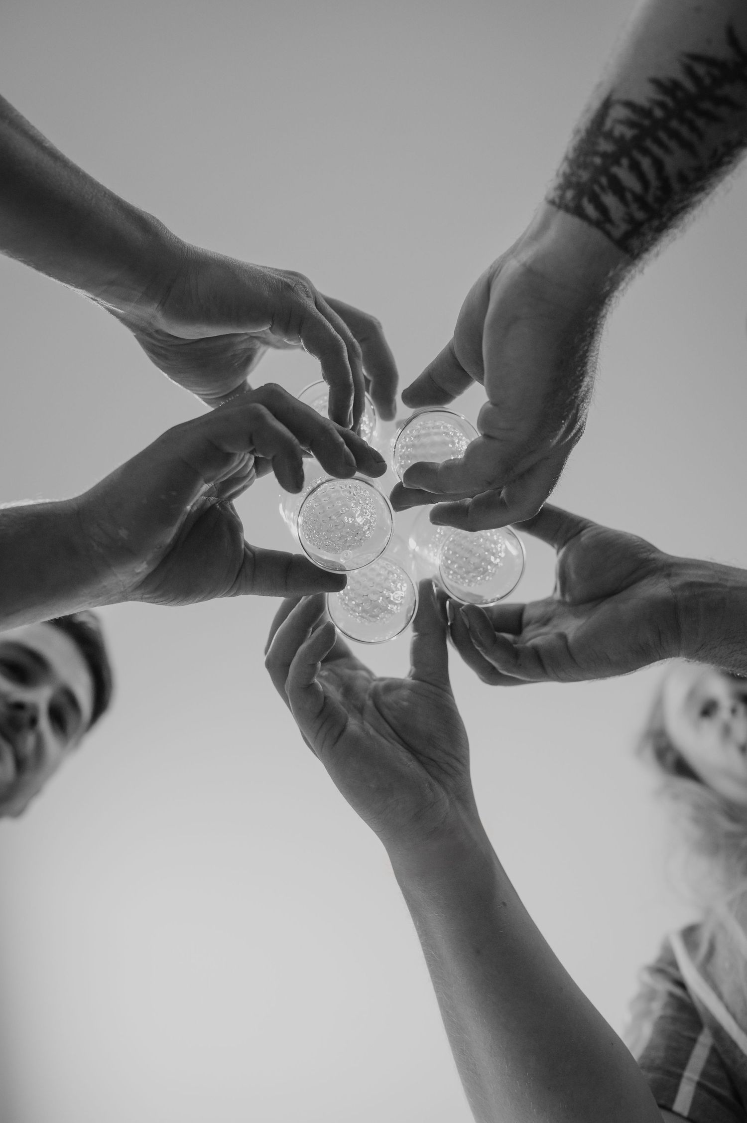 Multiple hands join together in a circle holding glowing hexagonal lights from below.