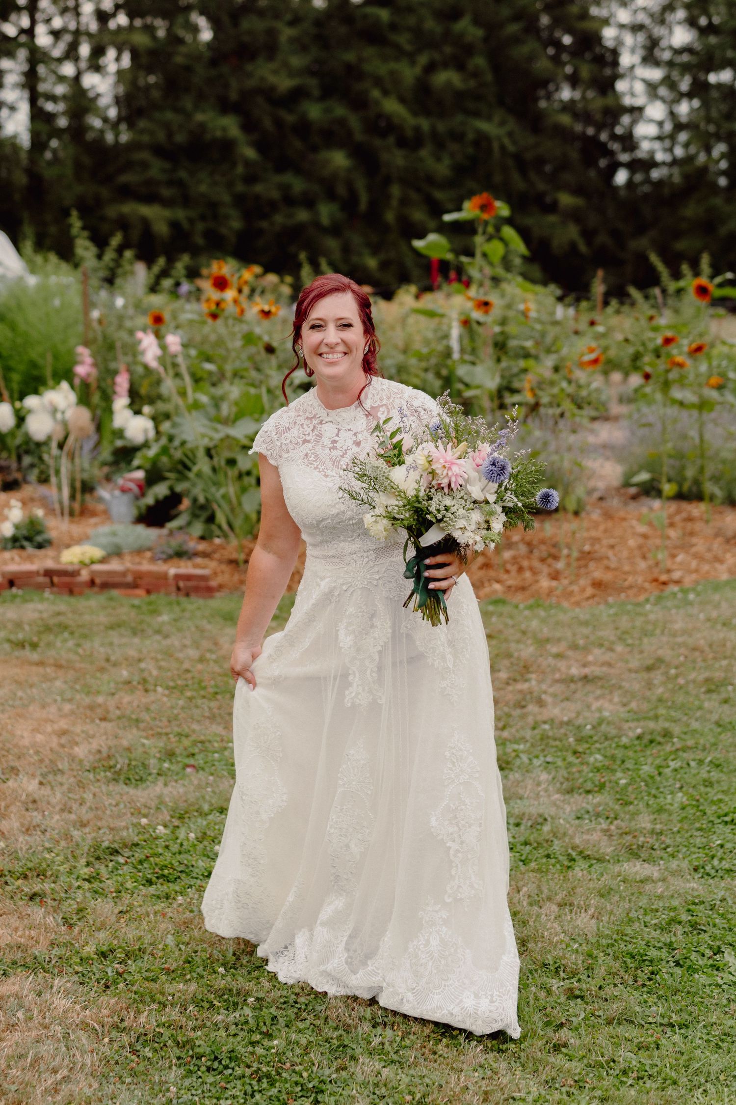 A beautiful wedding dress with lace details photographed in a garden filled with colorful flowers.