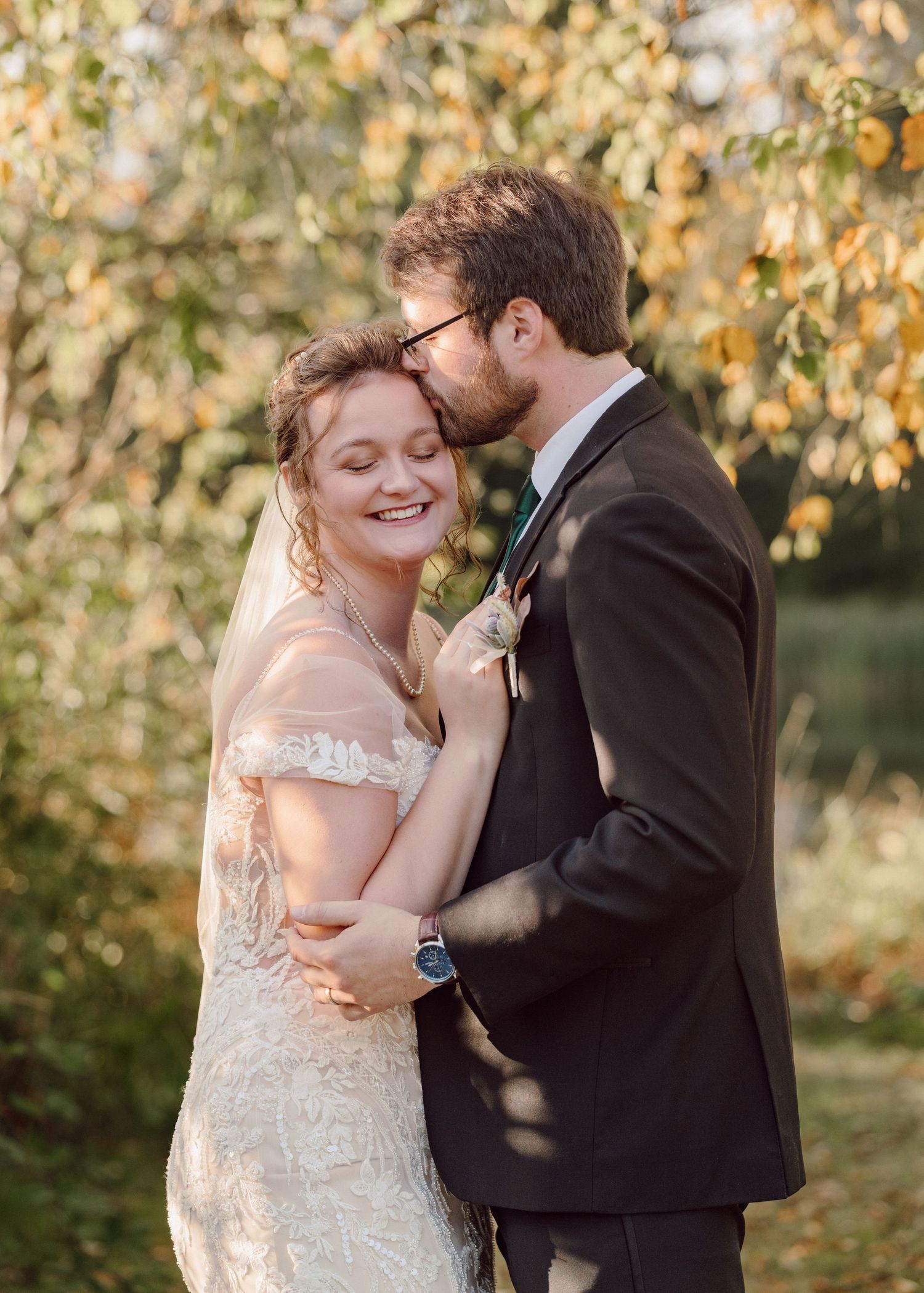 A tender moment between newlyweds with golden autumn leaves in the background.