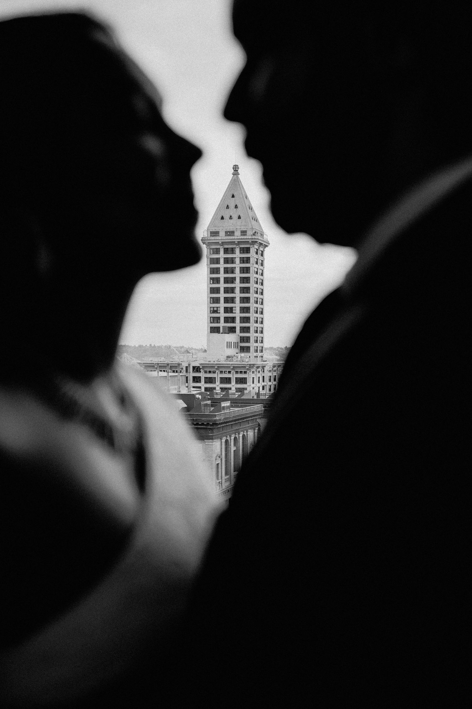 The Smith Tower in Seattle is framed between two silhouettes against a light background.