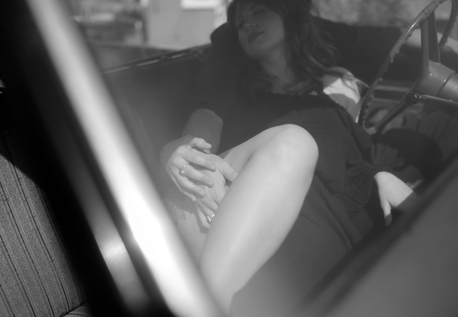 A moody black and white photo captures a quiet moment inside a car.