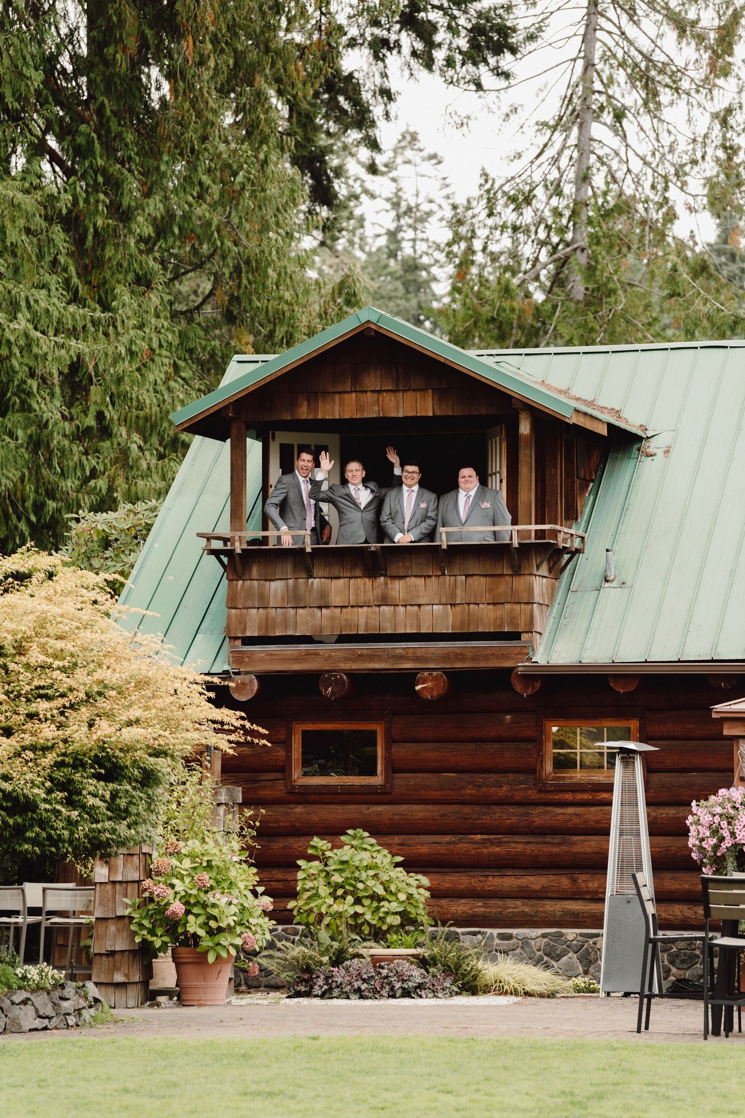 Rustic log cabin wedding venue with green metal roof and wooden exterior shown from multiple angles in a garden setting.