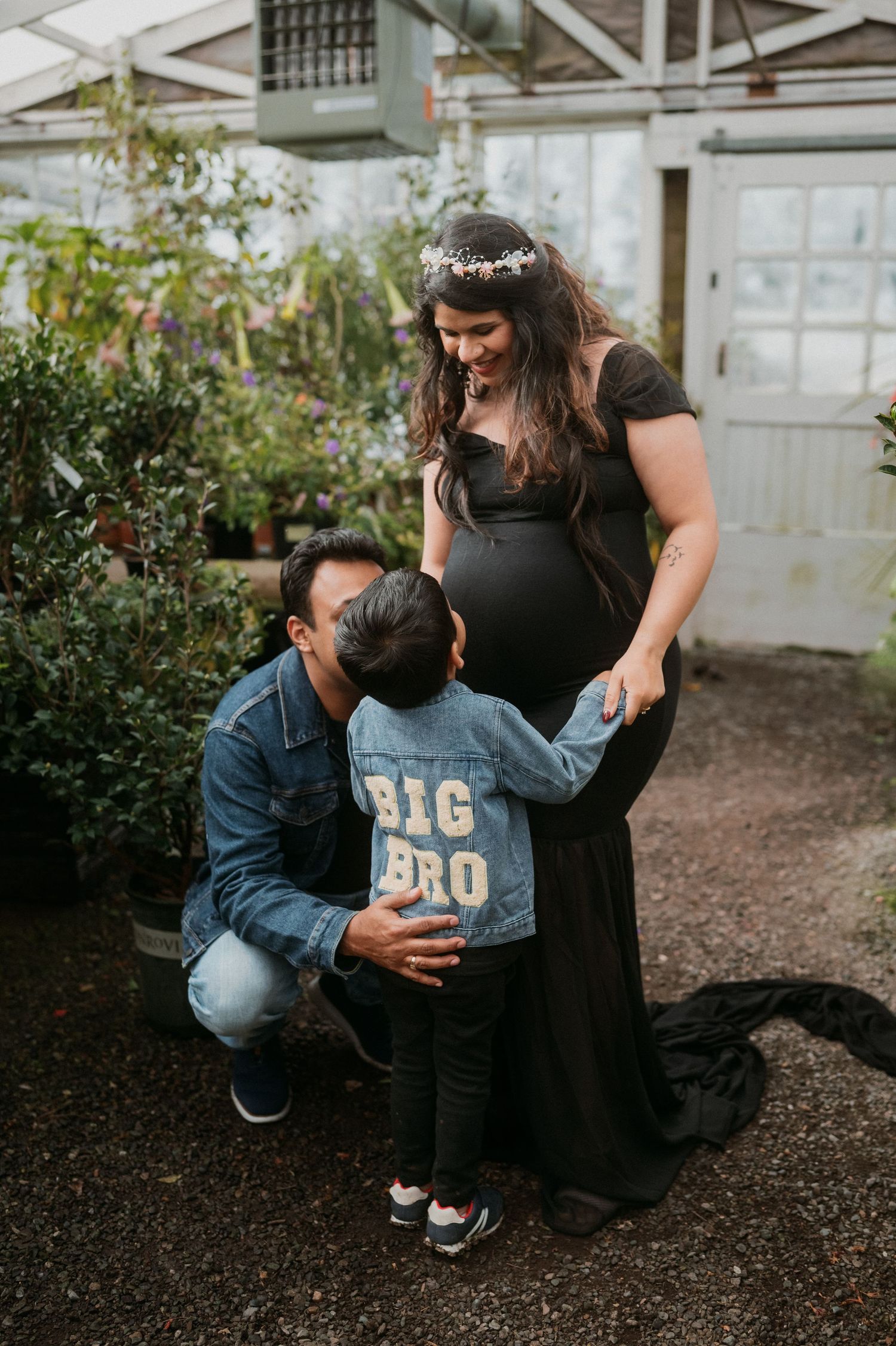 Family sharing tender moment together in greenhouse setting with plants around them.
