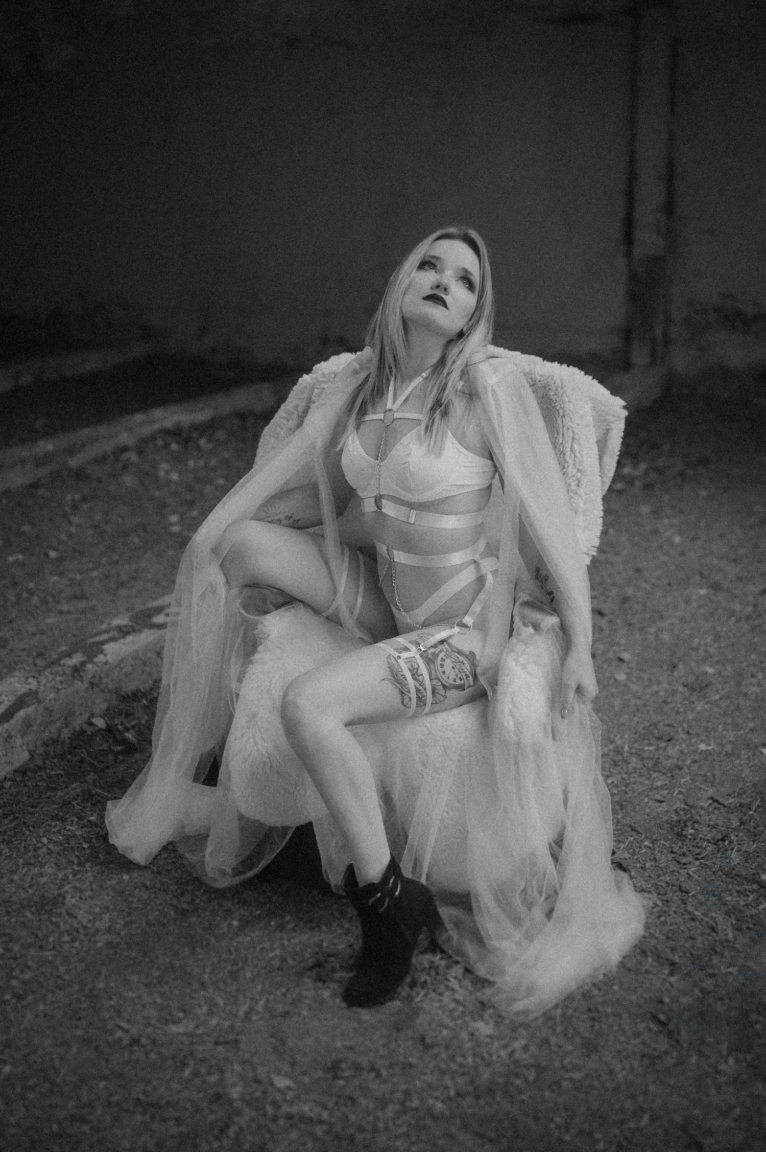 A person in a flowing white dress lies gracefully on the ground in a series of dramatic black and white artistic poses.