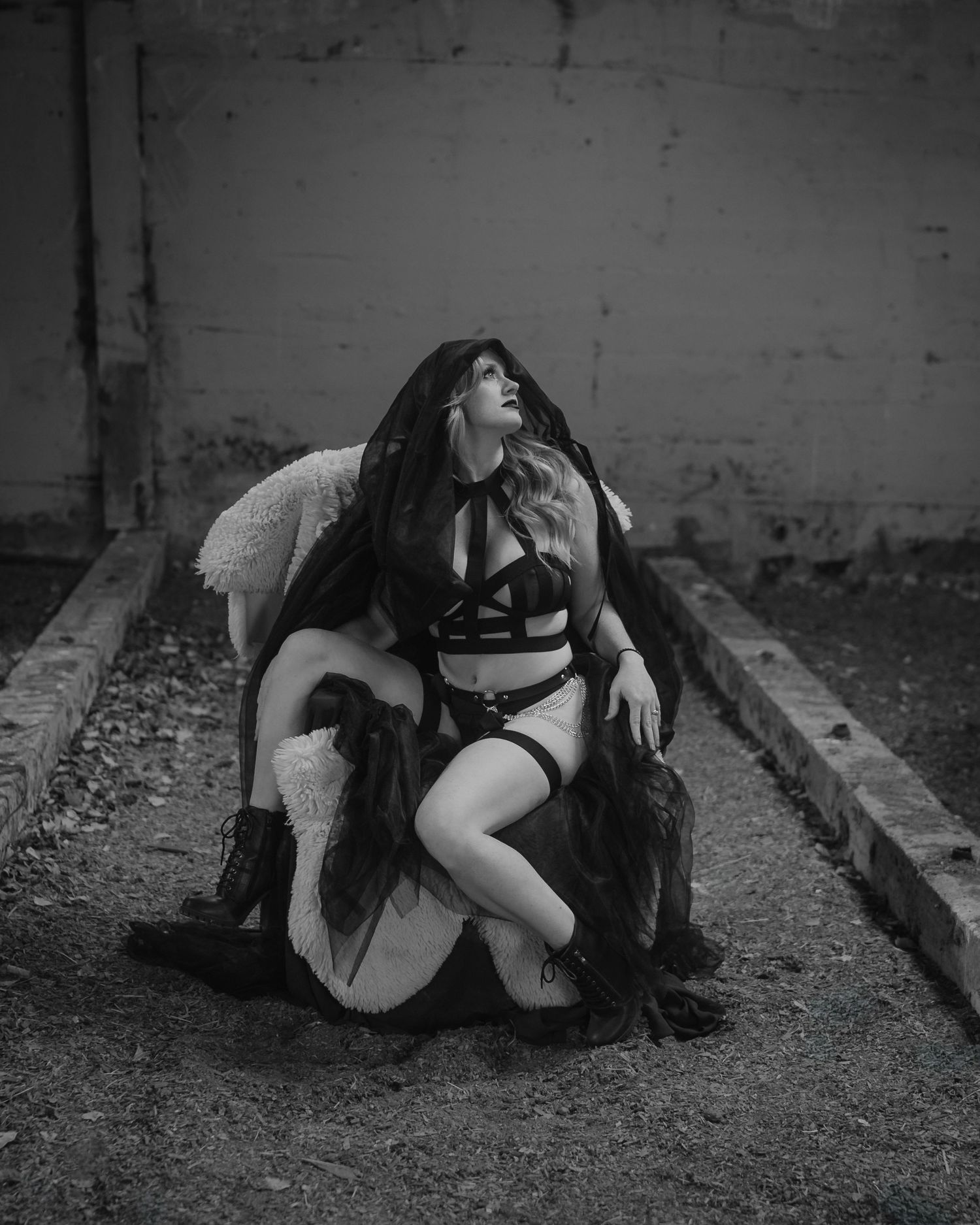 A series of black and white photographs showing someone laying near a stone wall with a banjo instrument in a moody setting.