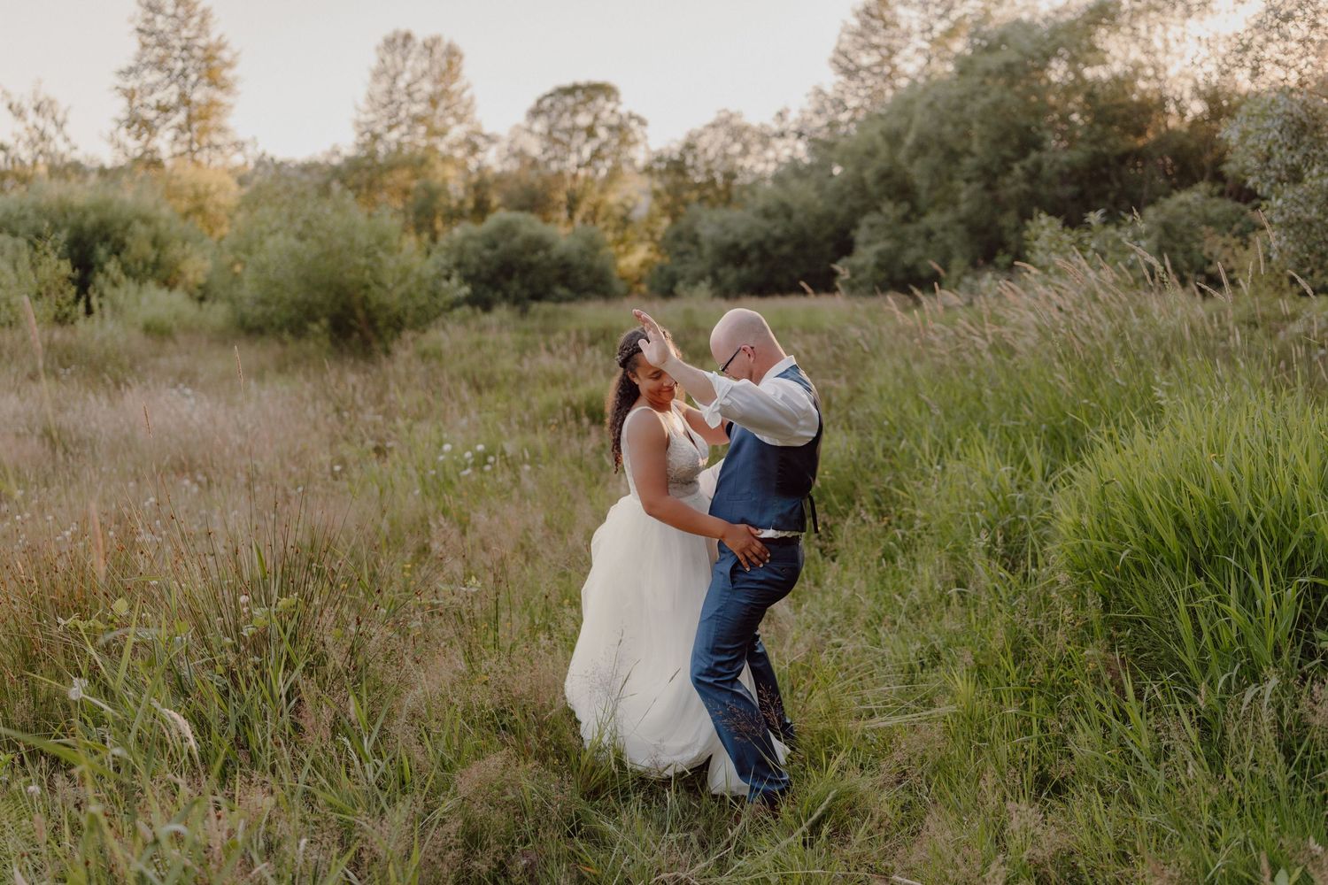 A couple shares a romantic dance moment in a rustic outdoor field setting.