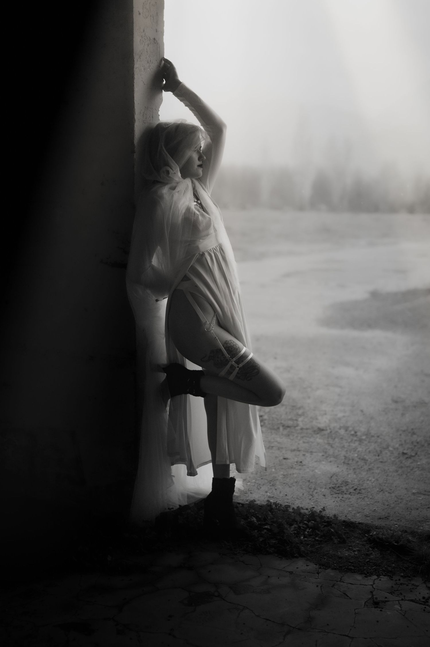 A misty black and white image sequence shows a small figure peeking around a corner in a moody, atmospheric setting.