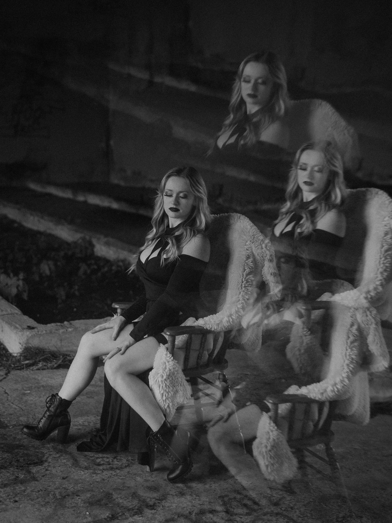 A black and white artistic portrait shows someone lounging in the grass wearing knee-high boots and flowing fabrics.