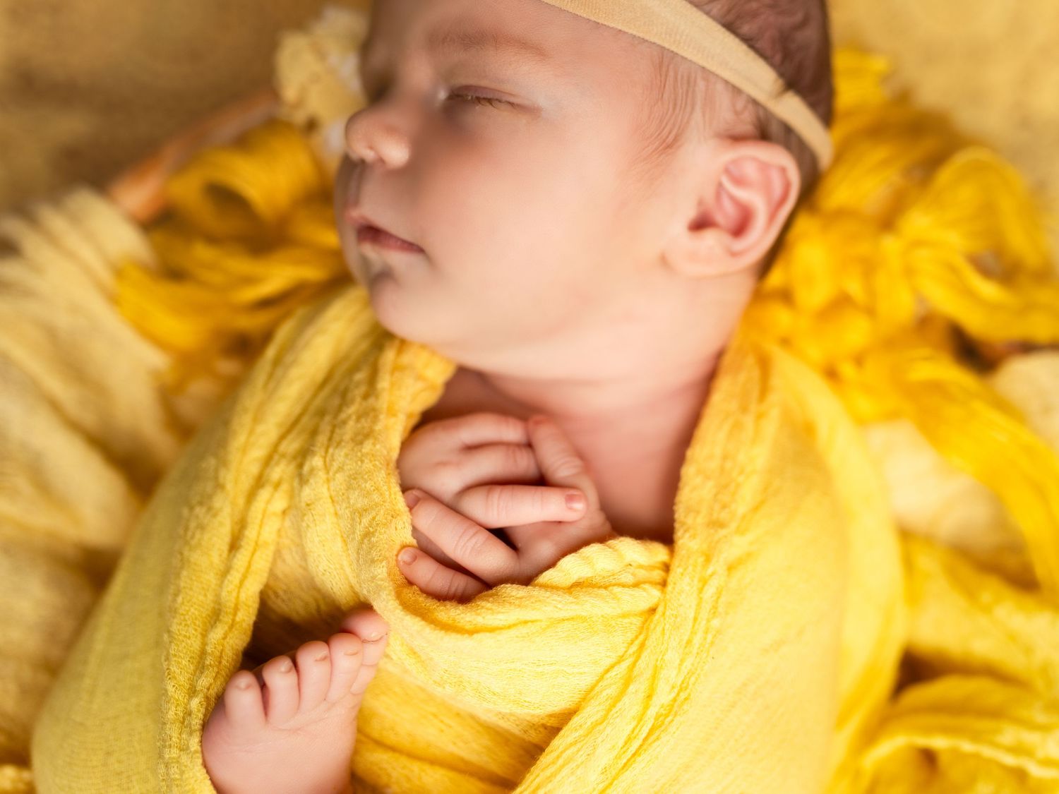 A baby wearing yellow clothing lies on a yellow blanket in a series of connected photos showing different poses.
