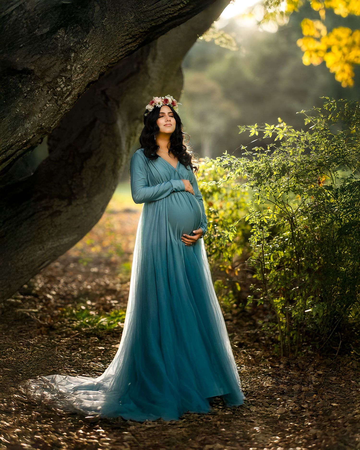 A dreamy maternity portrait featuring a turquoise dress against autumn foliage and natural light.