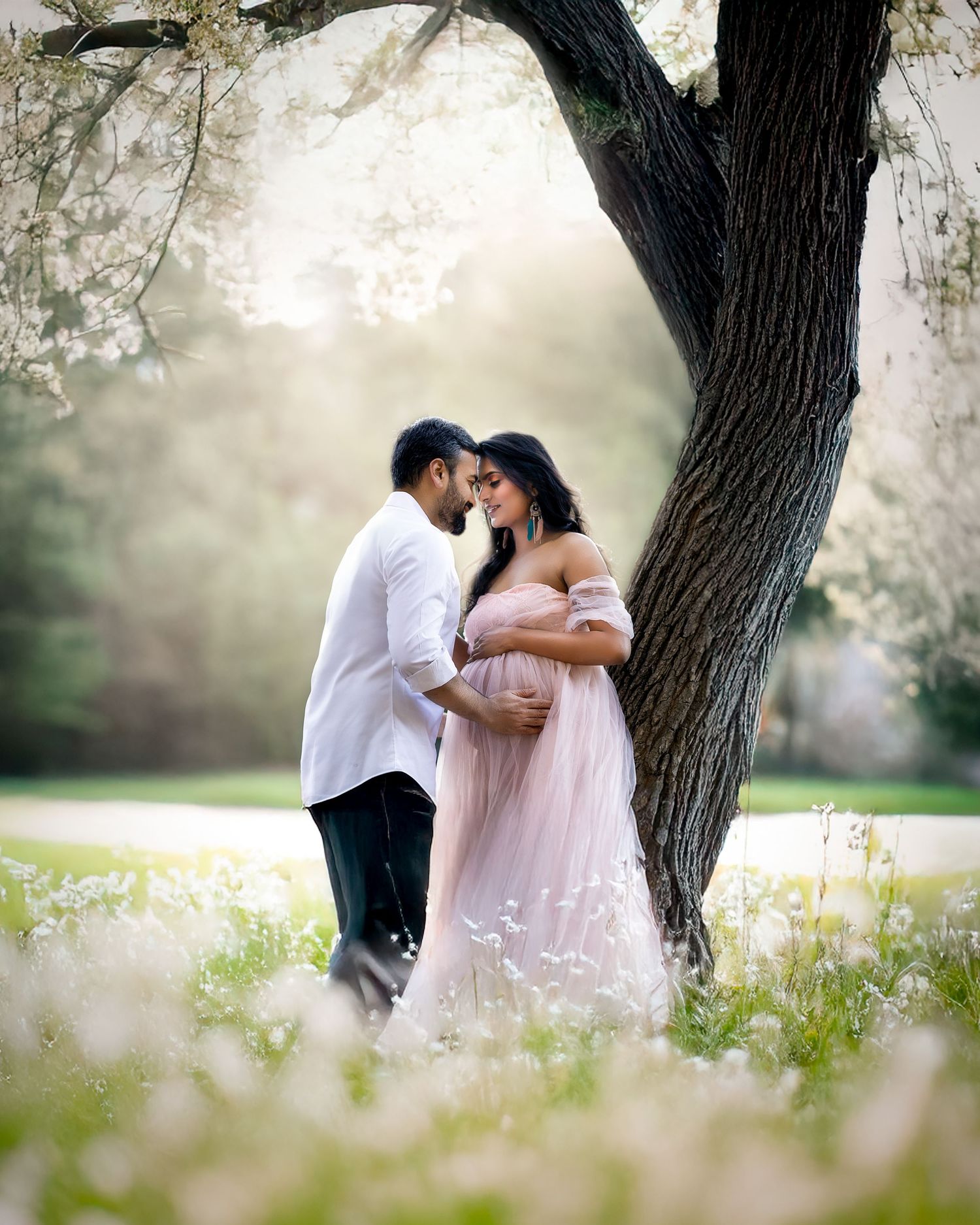 Romantic couple embraces under a blooming tree in springtime creating a dreamy outdoor portrait series.
