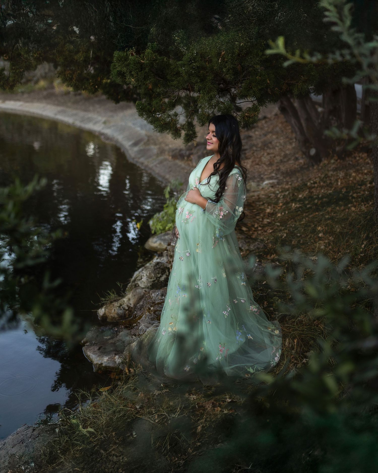 A dreamy photoshoot in a mint green dress by a reflective pond surrounded by autumn foliage.