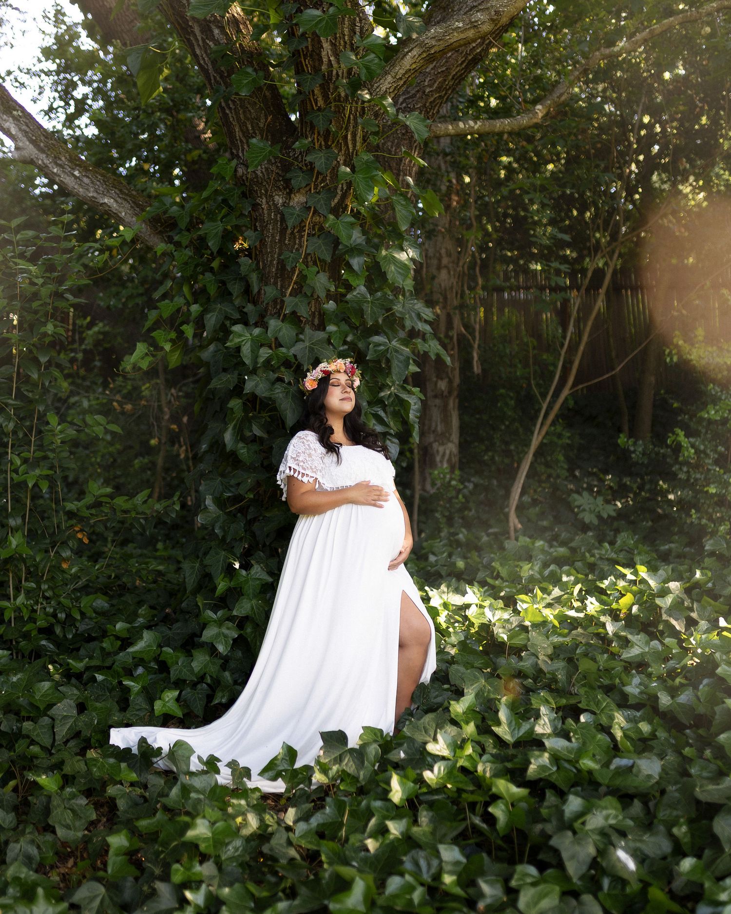 A couple embraces in a romantic moment against a backdrop of lush green foliage in a garden setting.