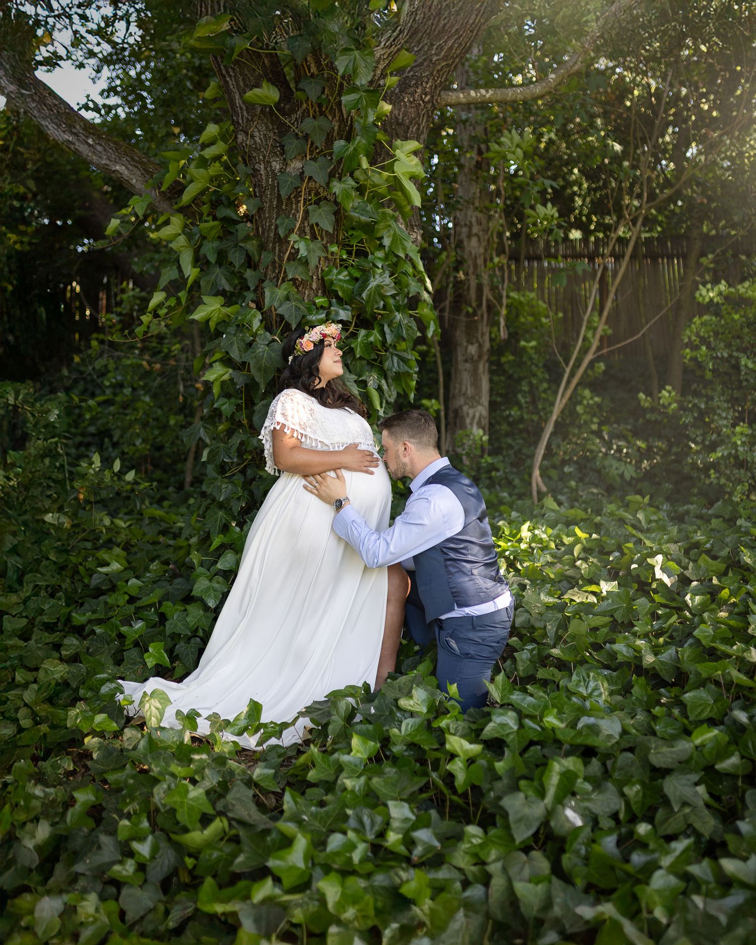 A couple shares an intimate moment in a lush garden setting with greenery surrounding them during their wedding day.