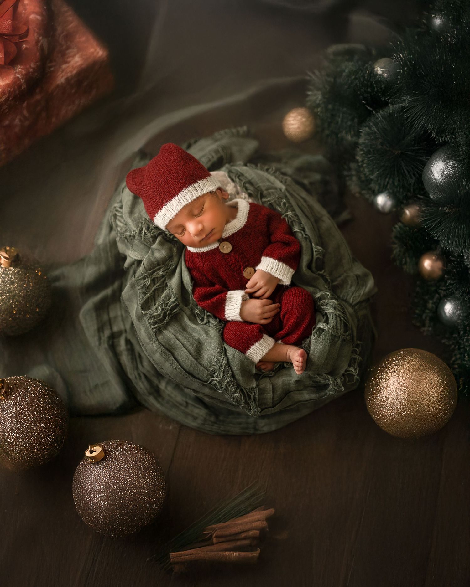Christmas ornaments and decorative items arranged on a dark surface with cinnamon sticks creating a cozy holiday scene.