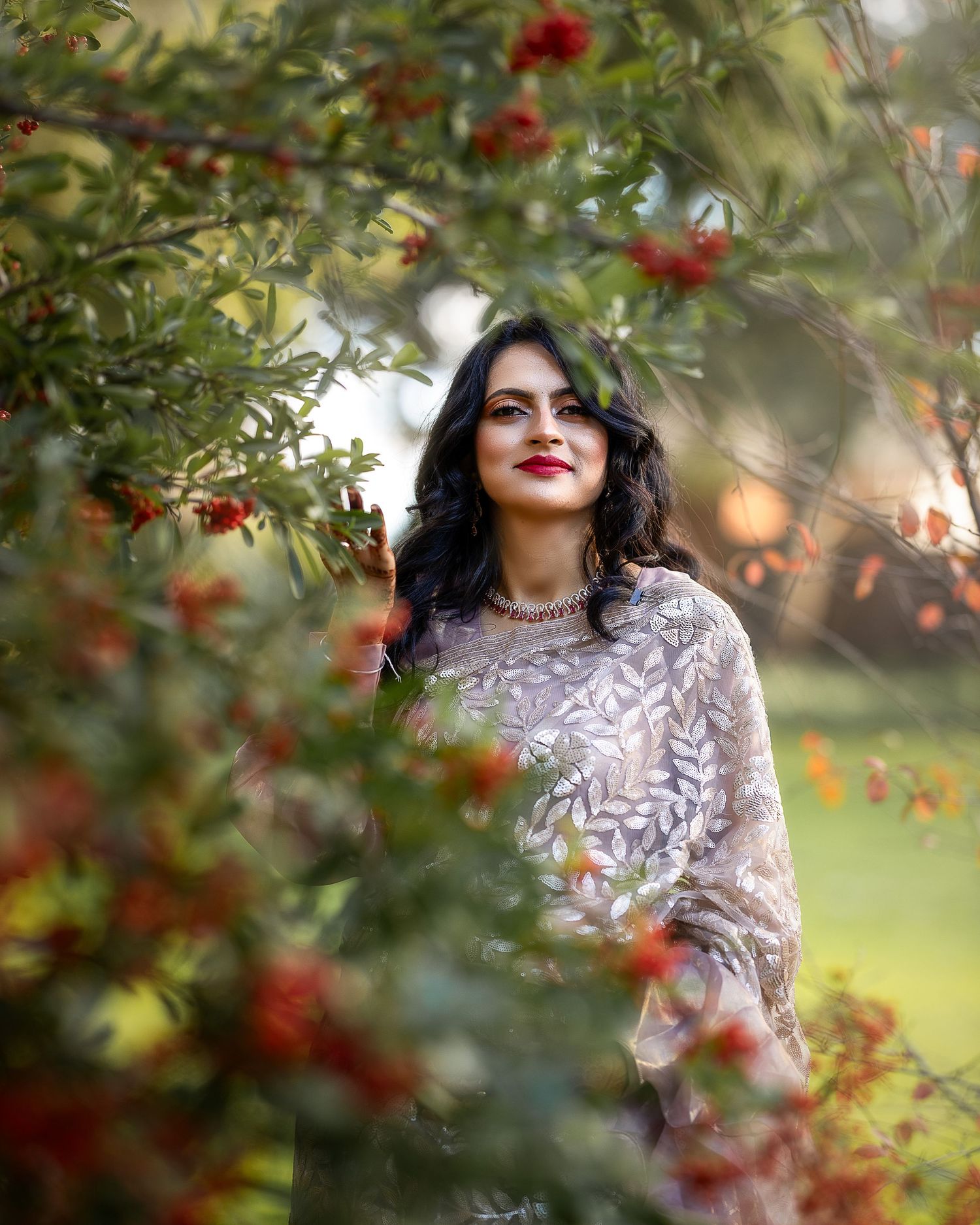 A series of romantic portraits among red berries and foliage showing a person in a delicate lace dress.