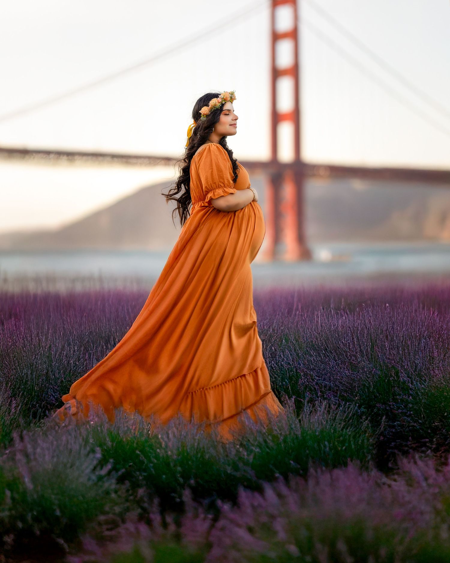 A flowing orange maxi dress stands out against purple lavender fields with the Golden Gate Bridge in the background.
