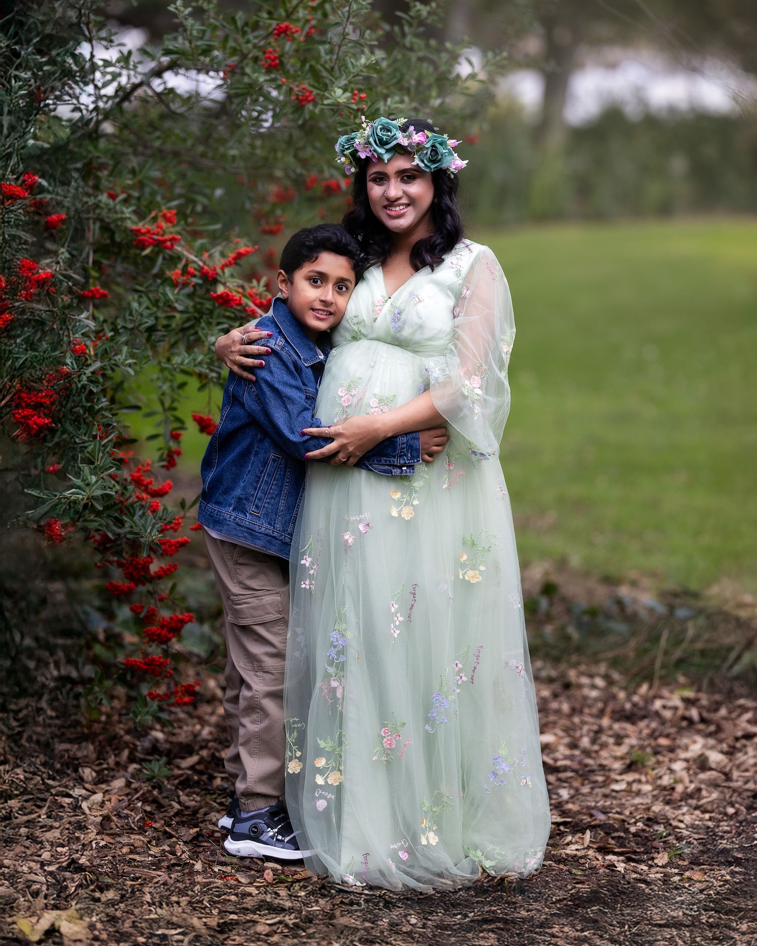 A sweet outdoor portrait showing tender moments near red berry bushes in a natural setting.