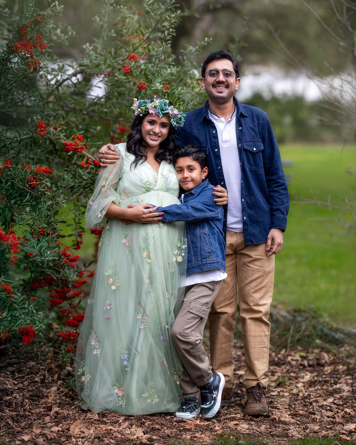 A family portrait in a garden with red berries, featuring coordinated casual and formal attire.