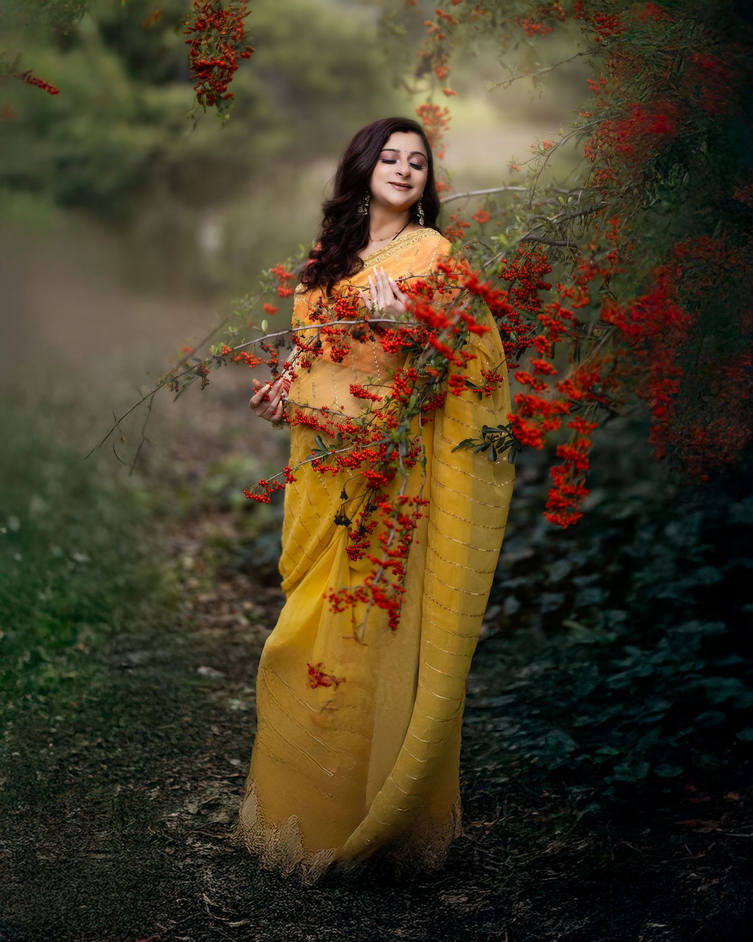 A figure in a flowing yellow dress poses gracefully among red autumn berries and foliage in a dreamy outdoor setting.